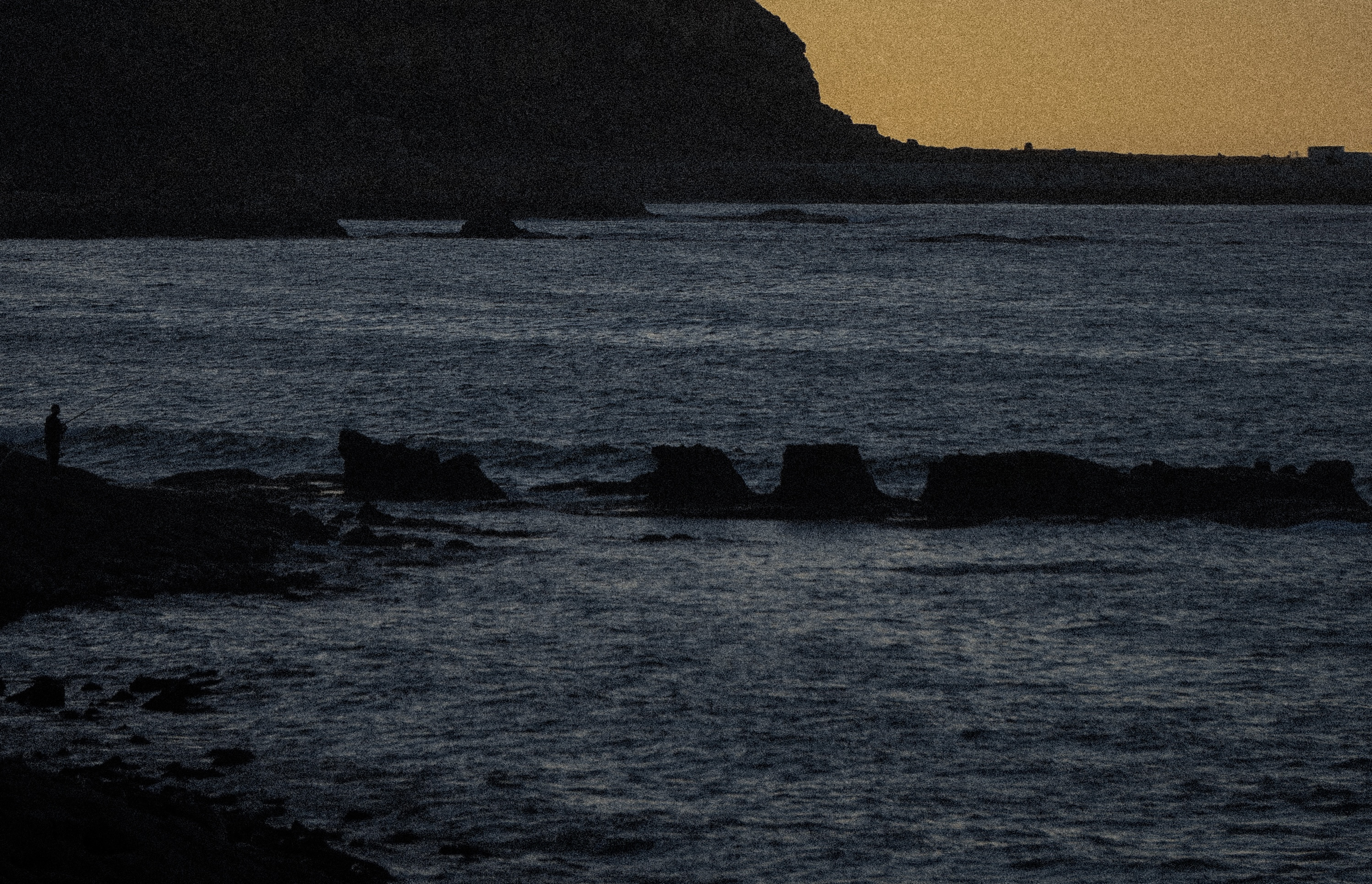 A lone figure at the water's edge as the light goes