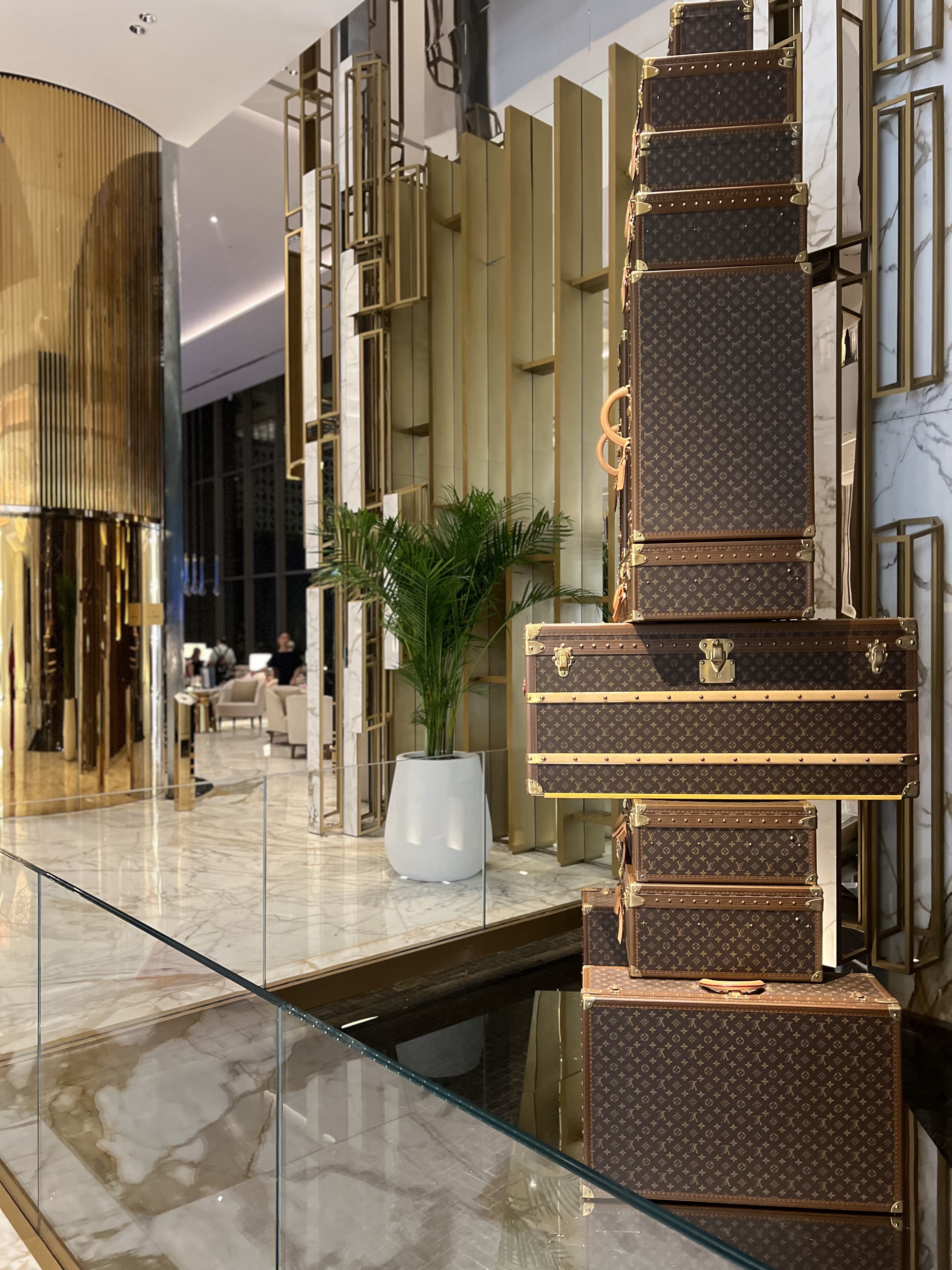 Louis Vuitton trunks stacked in a vitrine beside gold fluted columns in the lobby, Atlantis The Royal, Dubai