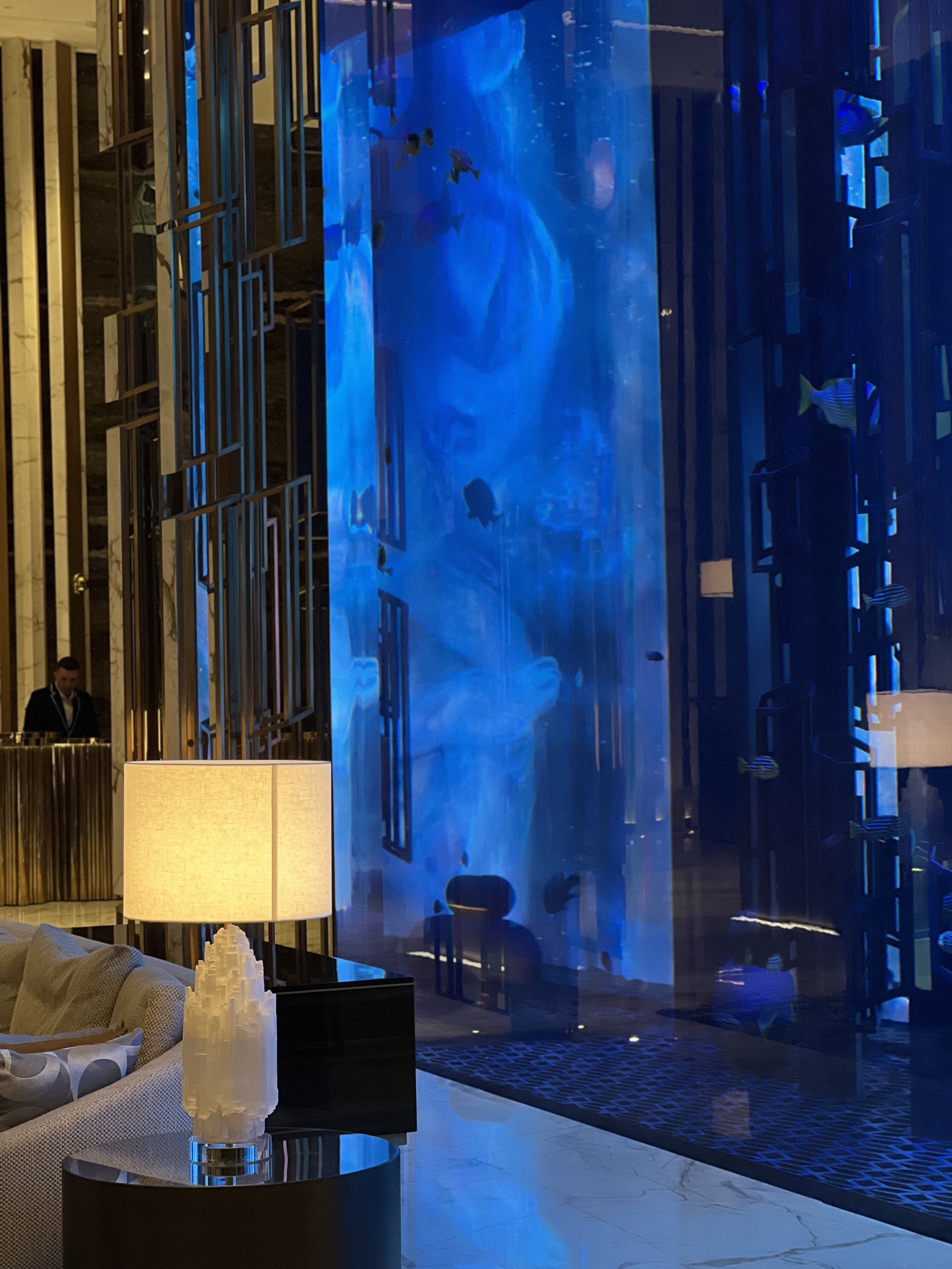 Floor-to-ceiling aquarium with fish and a white crystal mineral object on a side table in the lobby, Atlantis The Royal, Dubai