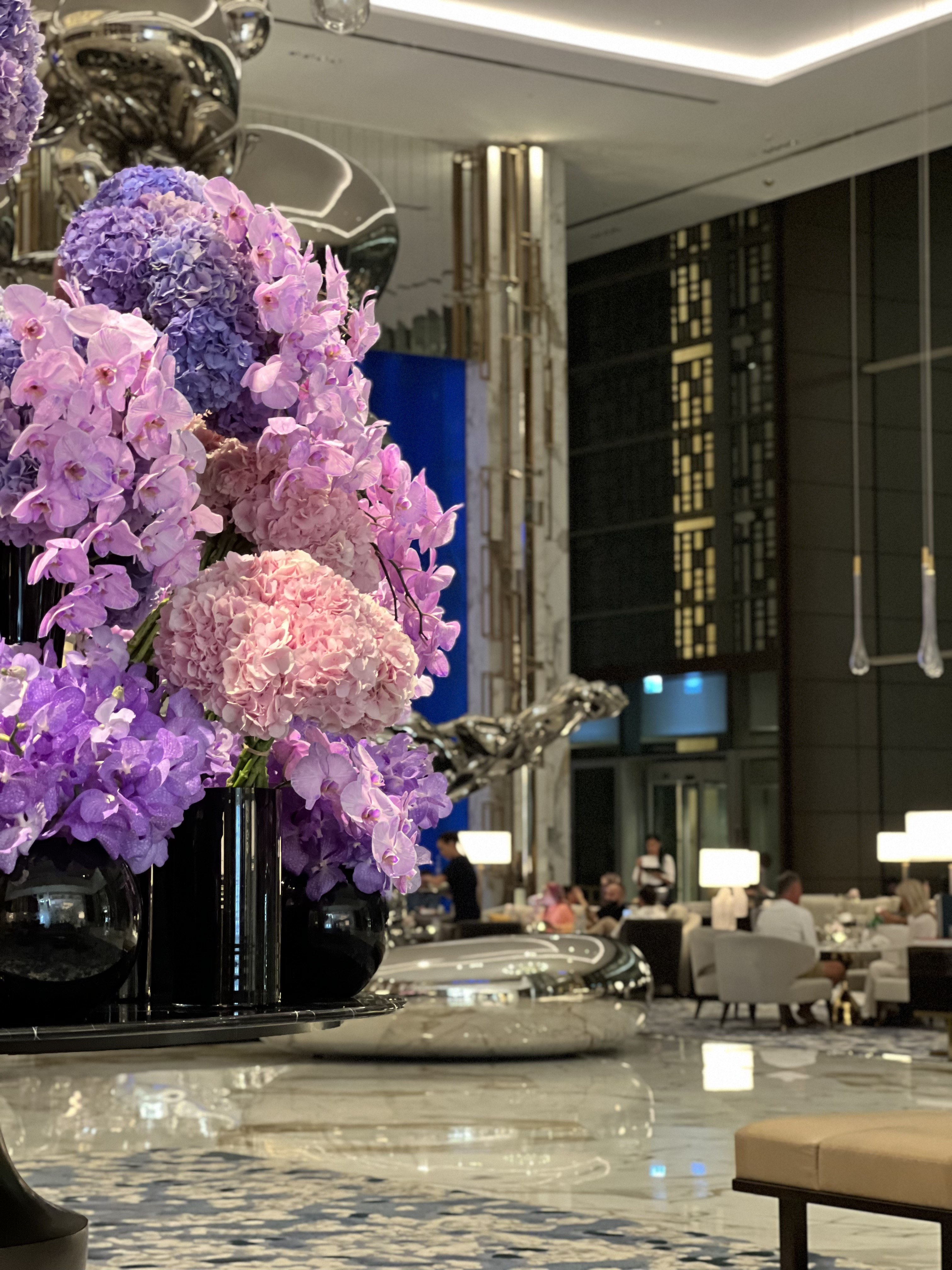Large arrangement of purple and pink hydrangeas and orchids in black vases in the lobby, Atlantis The Royal, Dubai