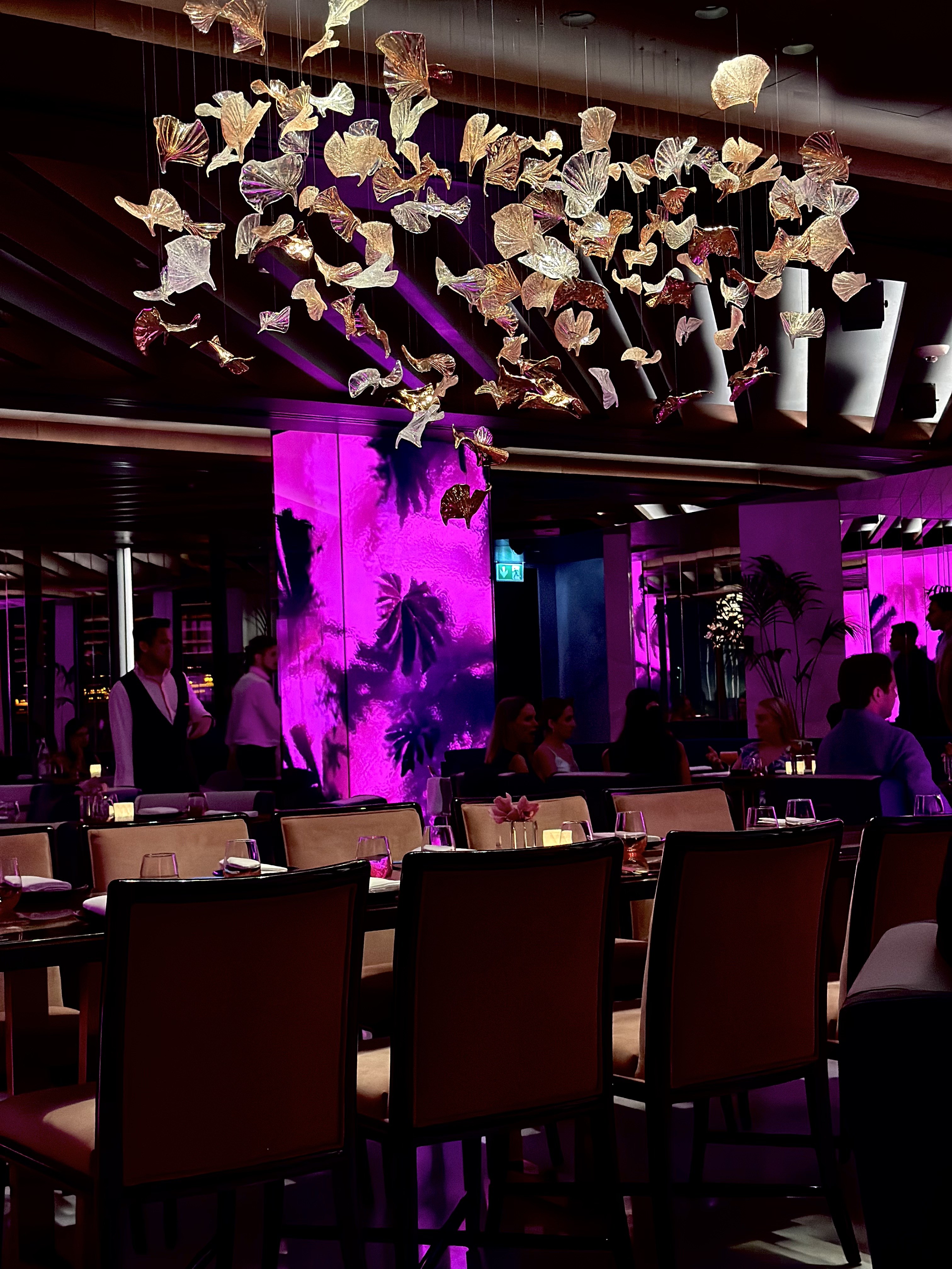 Dining room at night with pink and magenta lighting and shell and fan ceiling installation, Atlantis The Royal, Dubai