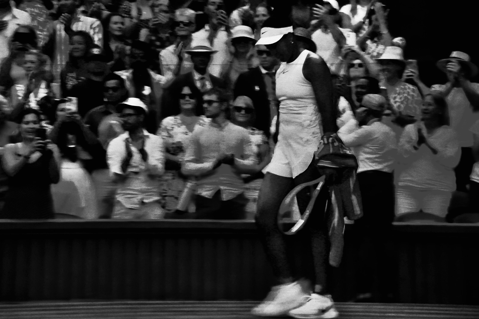 A player passing before the crowd, racquets carried under one arm