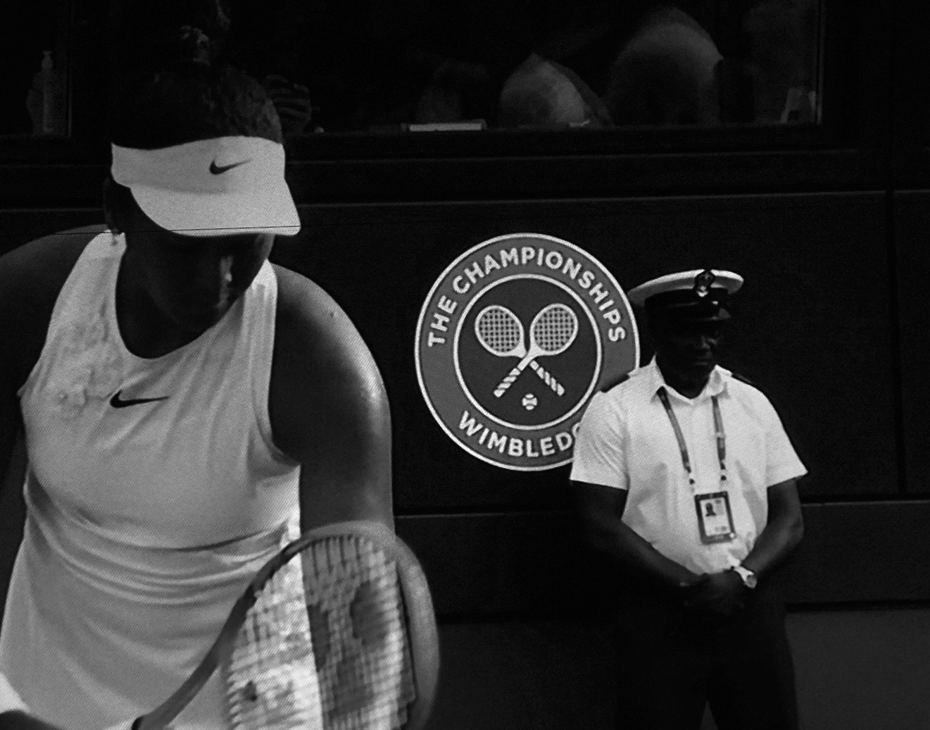 A player waiting beside the championship mark, an official standing in shadow