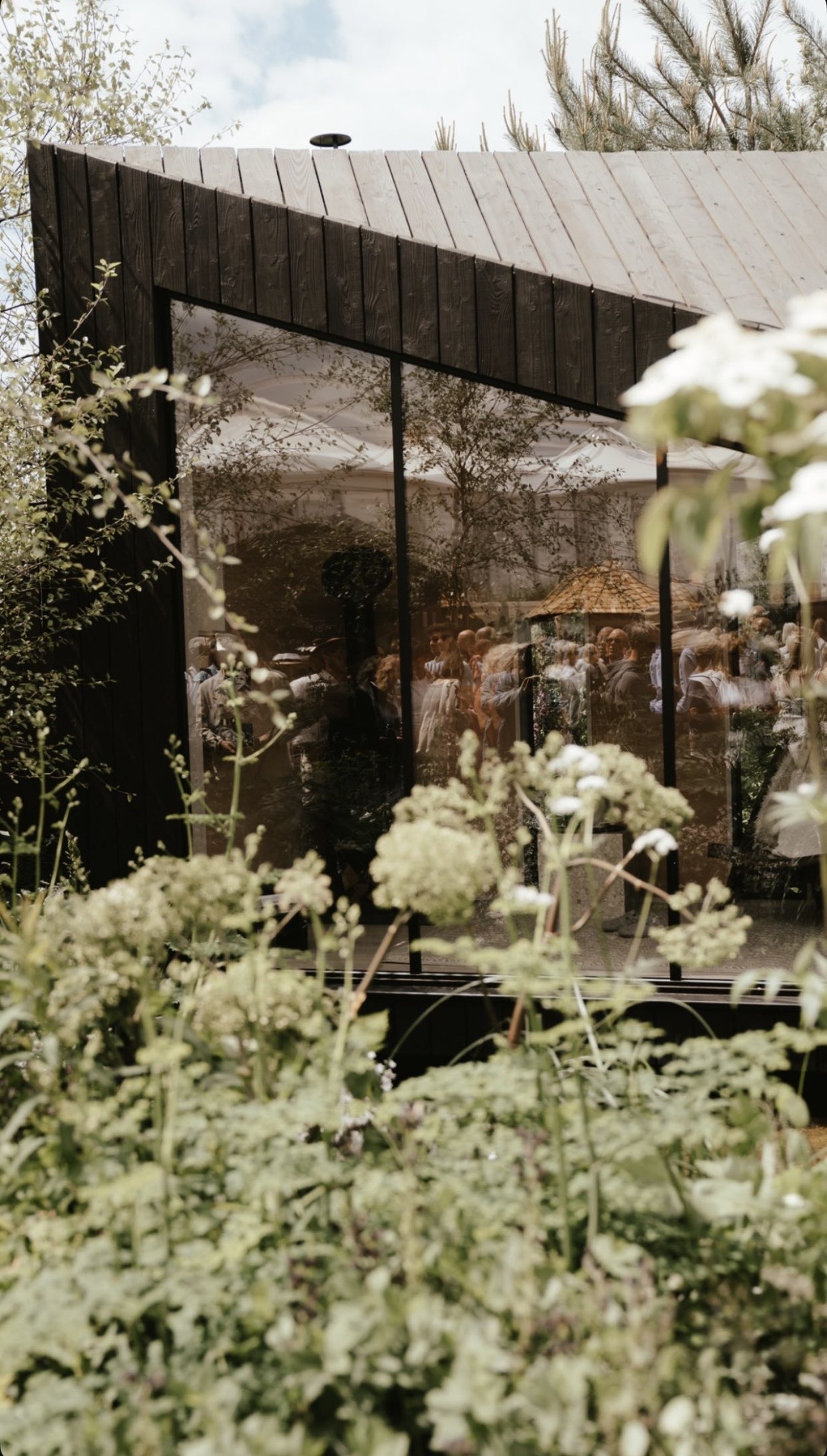 Glass pavilion reflecting the garden and crowd, RHS Chelsea Flower Show 2022, London