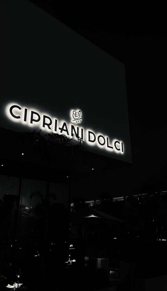 Cipriani Dolci sign glowing white against a dark night sky, Doha