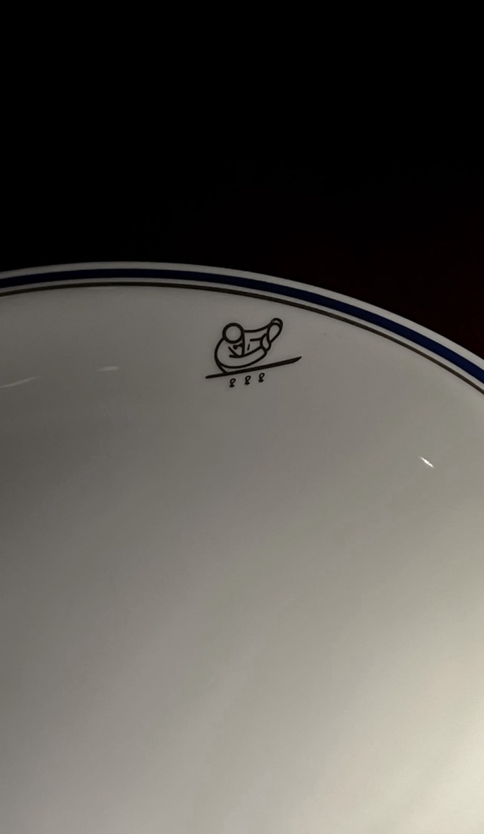 White Cipriani plate with blue trim and gondolier logo on a dark surface, Cipriani Dolci, Doha