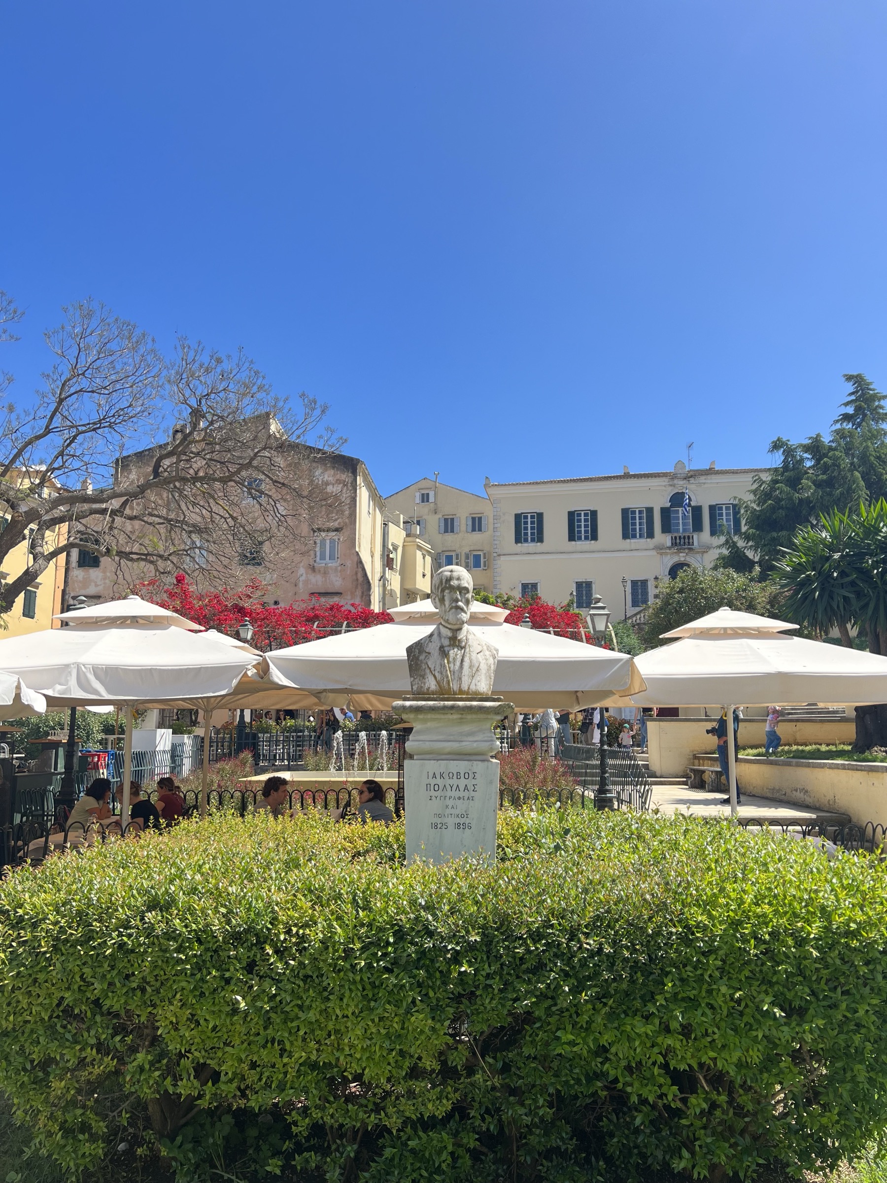 Town square with statue and café umbrellas, Corfu