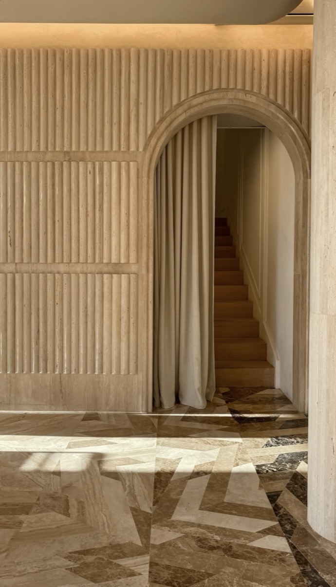Travertine arch with curtain and staircase beyond, polished marble floor, Dubai