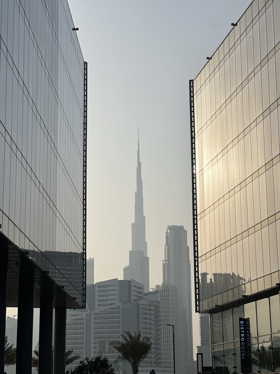 Burj Khalifa in midday haze framed between two glass towers, Dubai