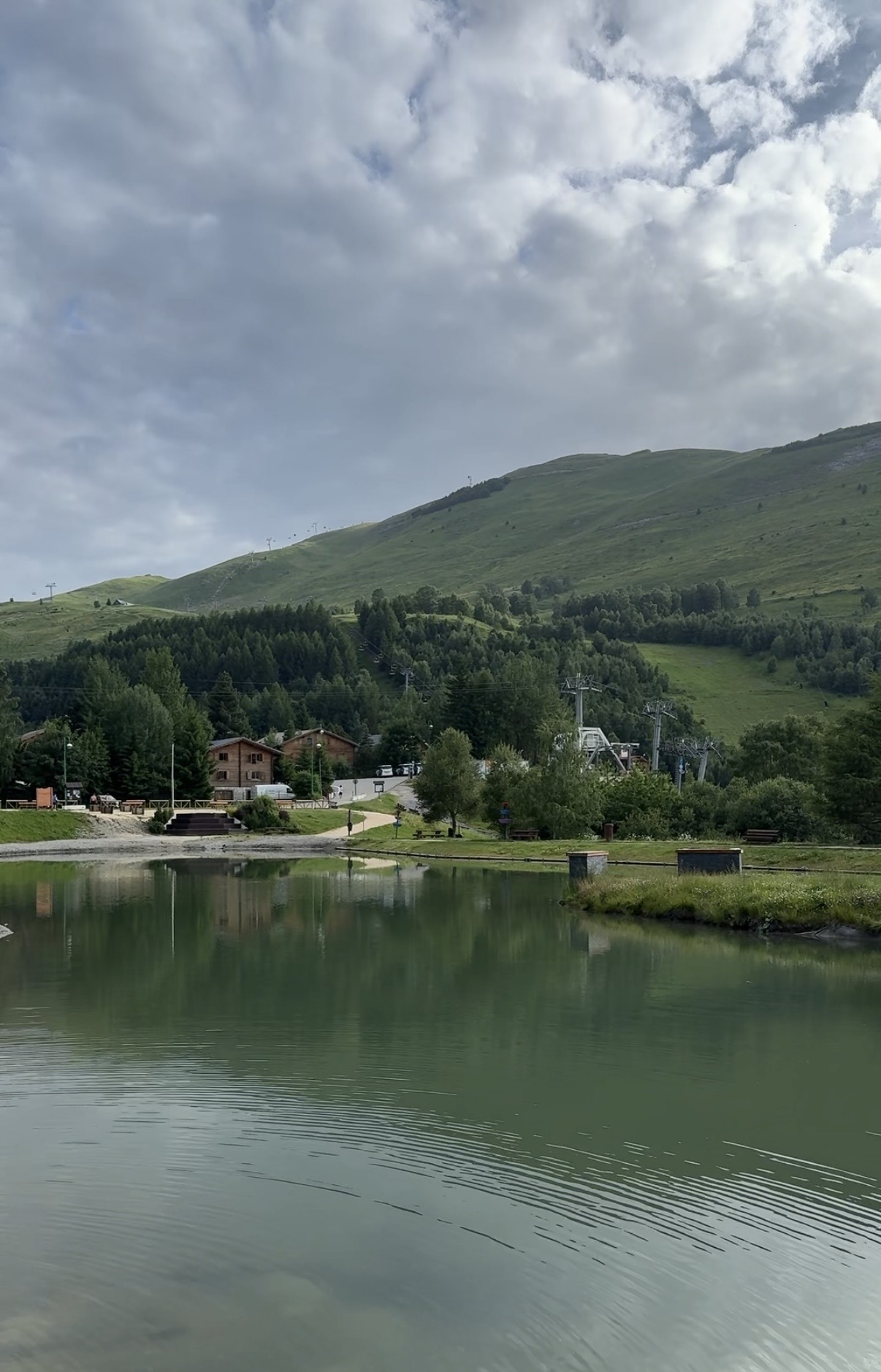 Lake with chalet and green hillside, French Alps