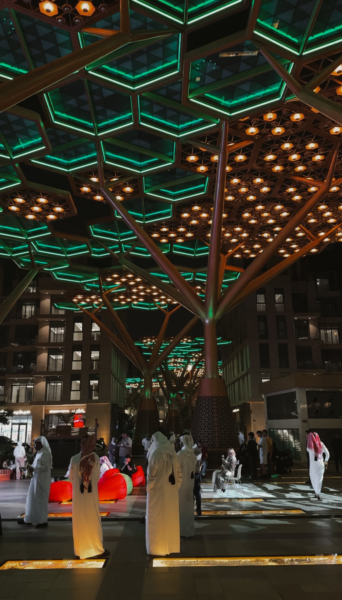 An evening crowd gathered under green canopies, Gewan Island, Doha