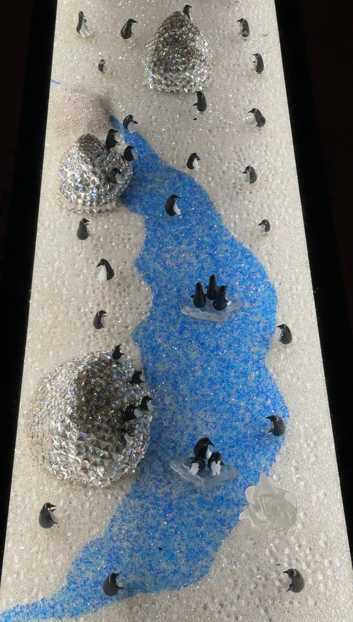 A mosaic of penguins crossing blue ice, Gewan Island, Doha