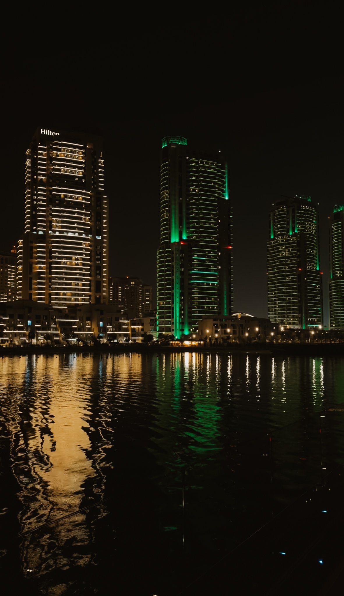 Lit towers reflected across the dark water, seen from Gewan Island, Doha