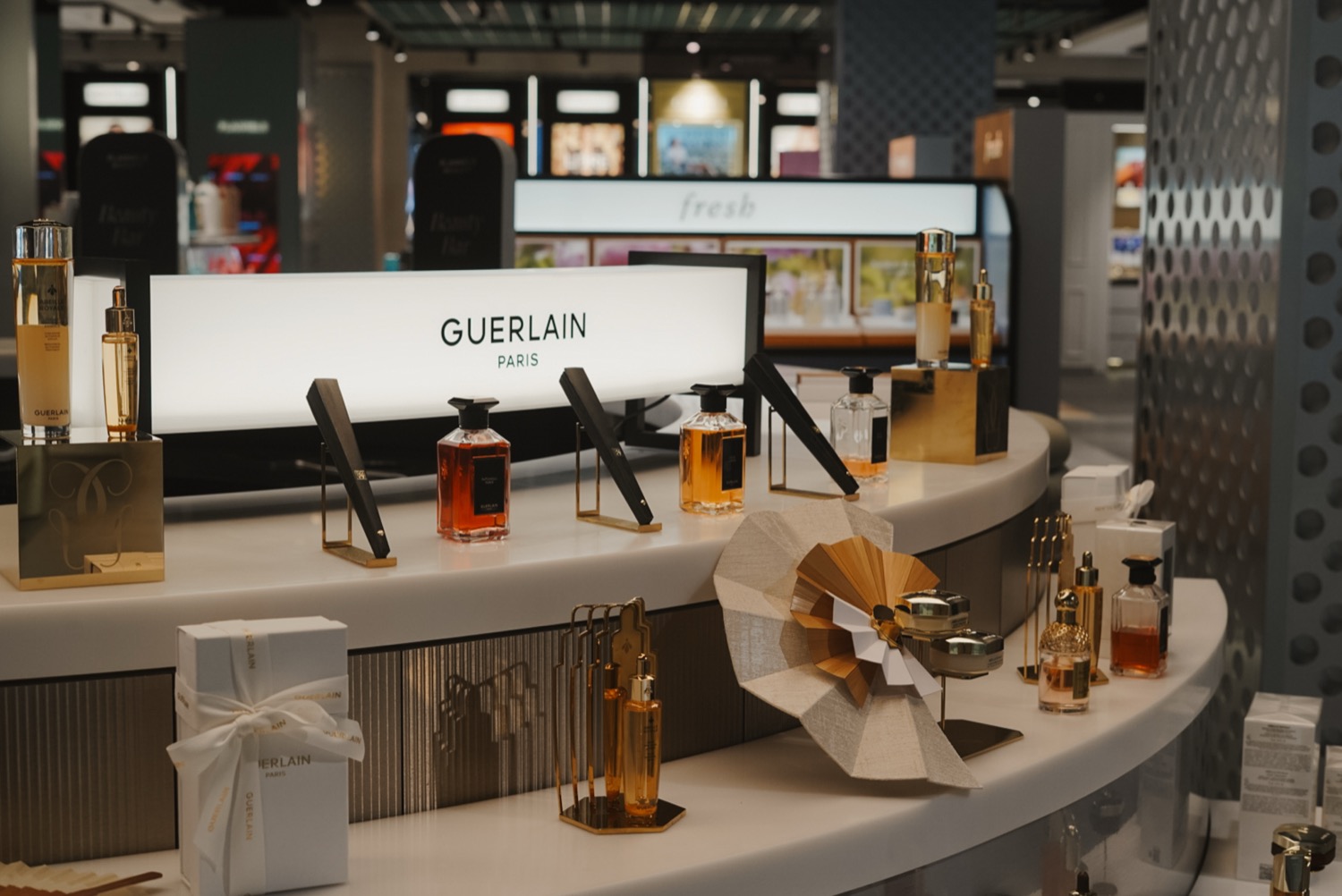 Guerlain counter with illuminated lightbox and fragrance bottles on display, Leeds