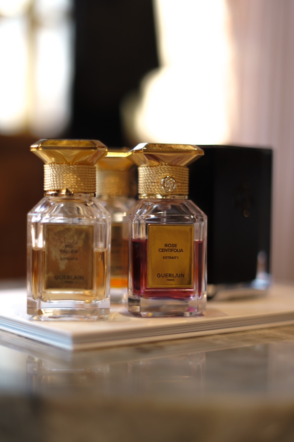 Gold-capped Guerlain extrait bottles gathered on a marble table, Leeds