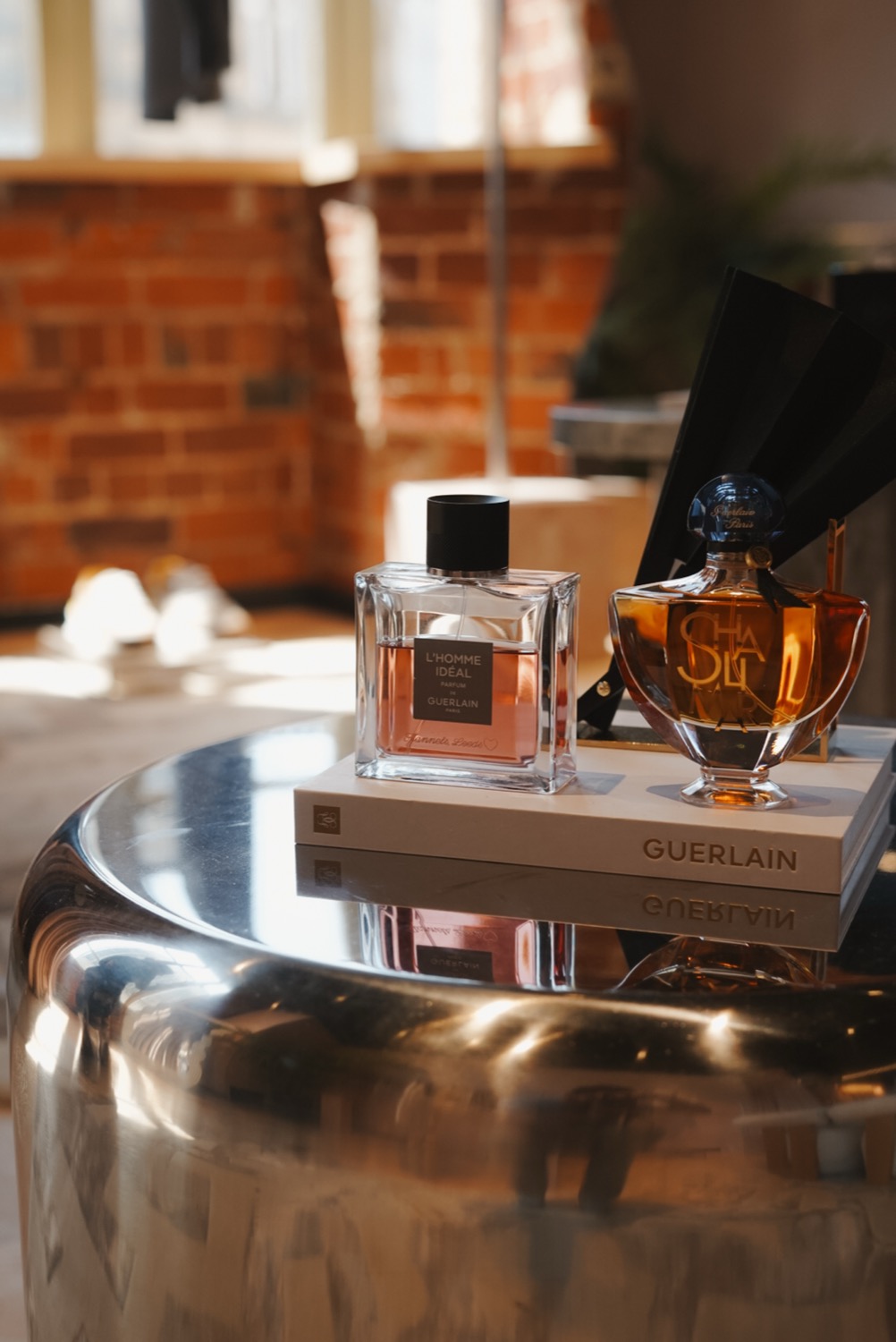 L'Homme Idéal and Shalimar bottles on a Guerlain book on a polished steel table, Leeds
