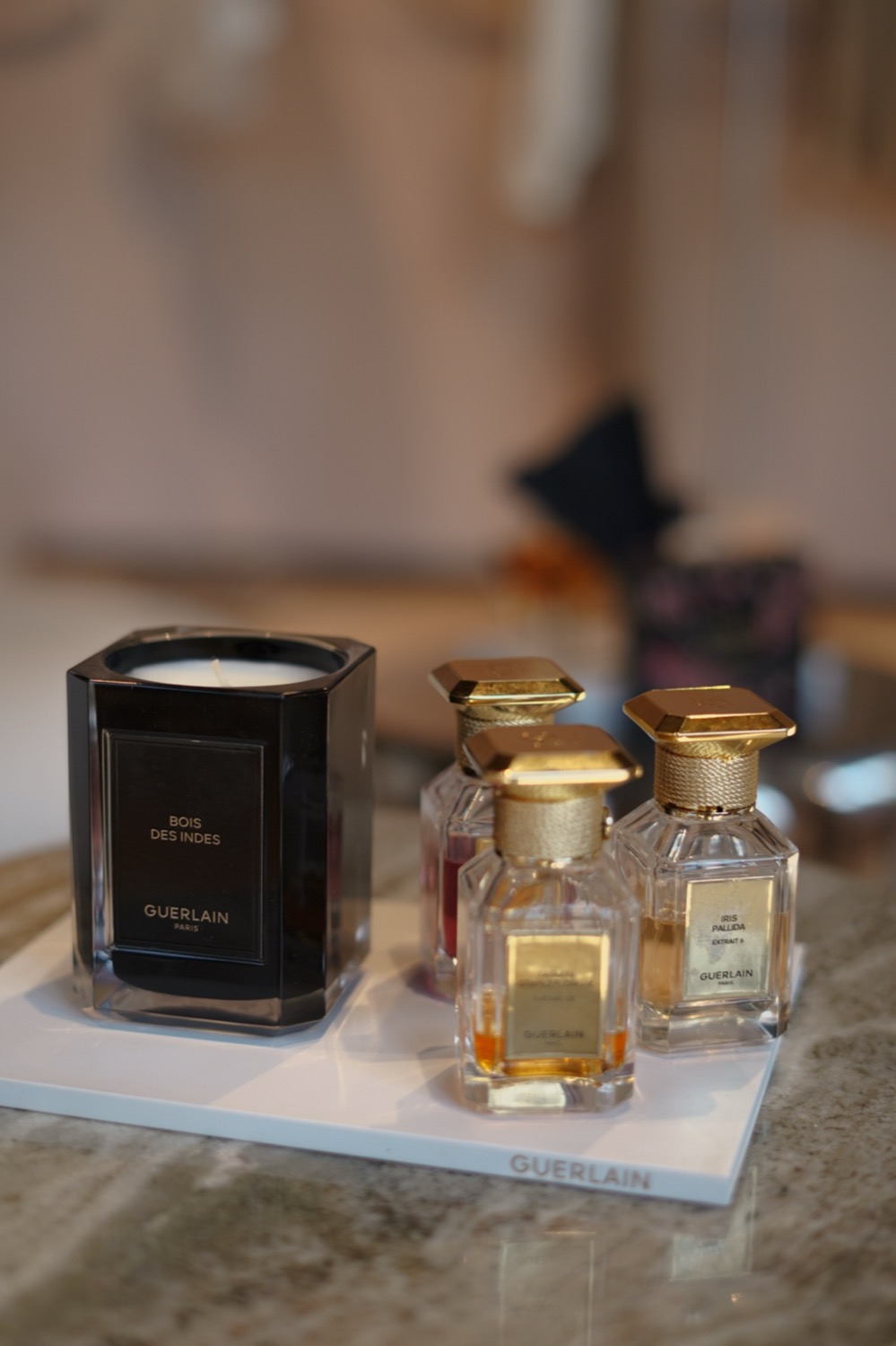 Bois des Indes candle beside extrait bottles on a white Guerlain tray, Leeds
