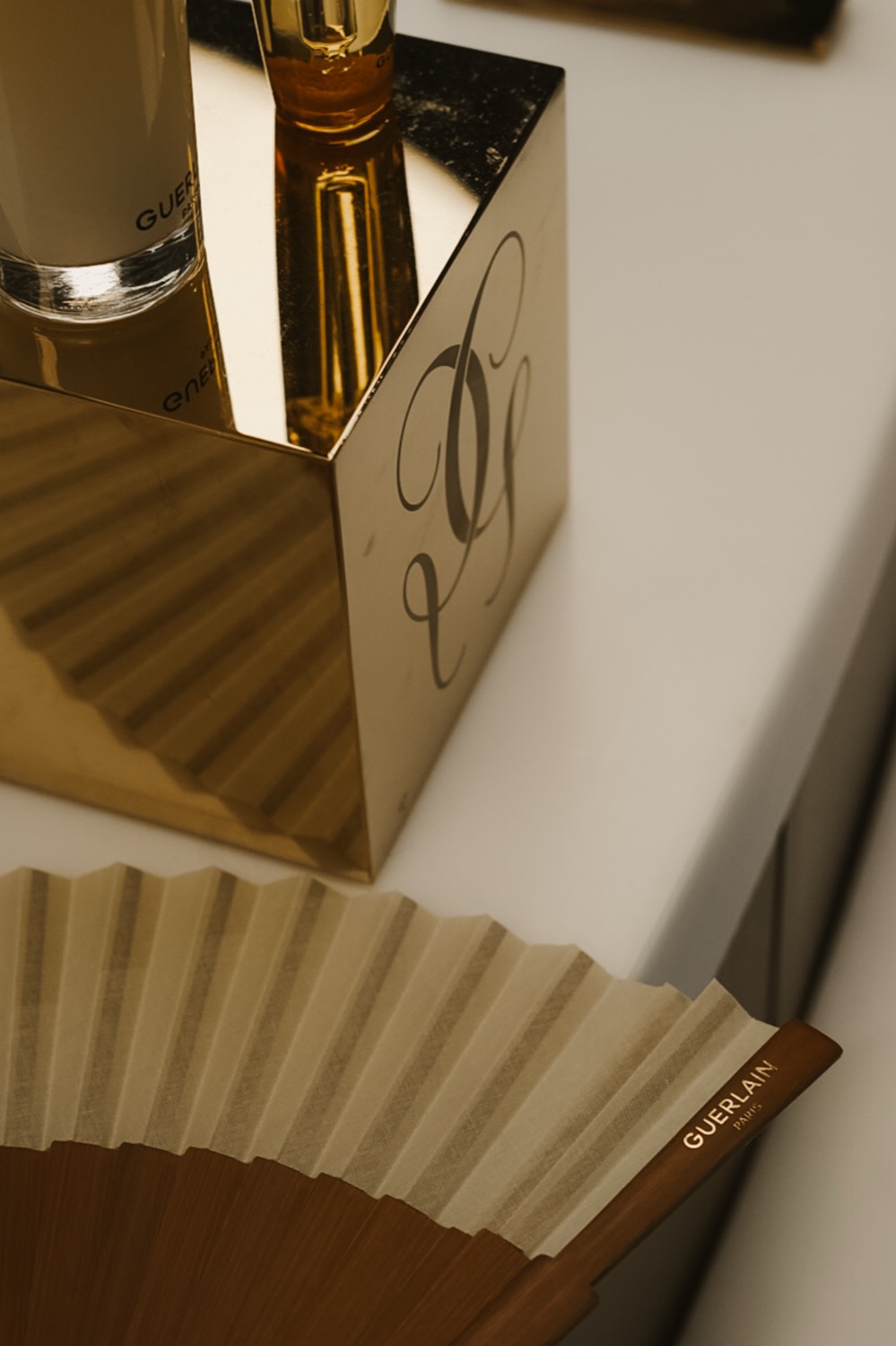 Engraved gold cube and Guerlain paper fan seen from above, Leeds