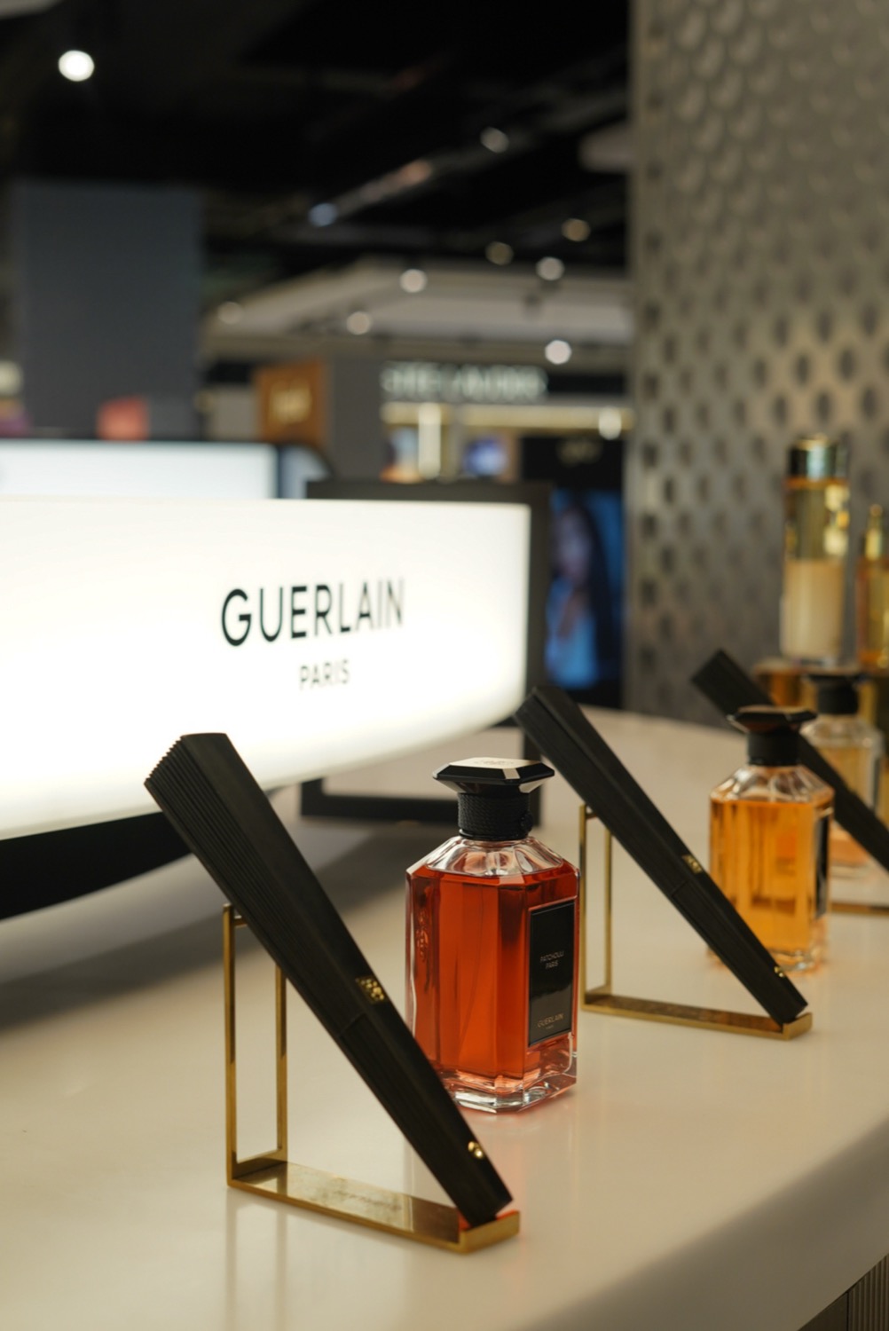 Black fans and fragrance bottles before the Guerlain lightbox, Leeds