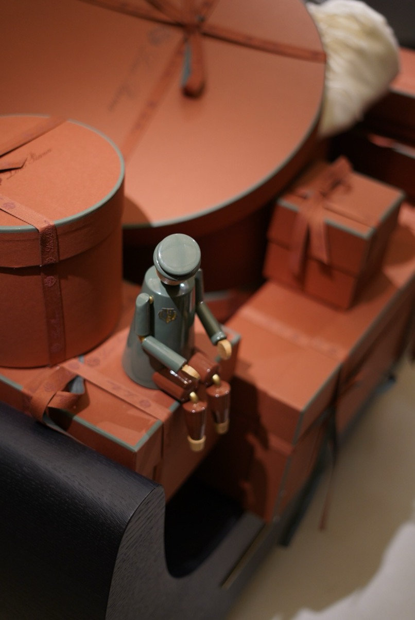 Miniature Harrods doorman figure among terracotta gift boxes in a window display, Harrods, London