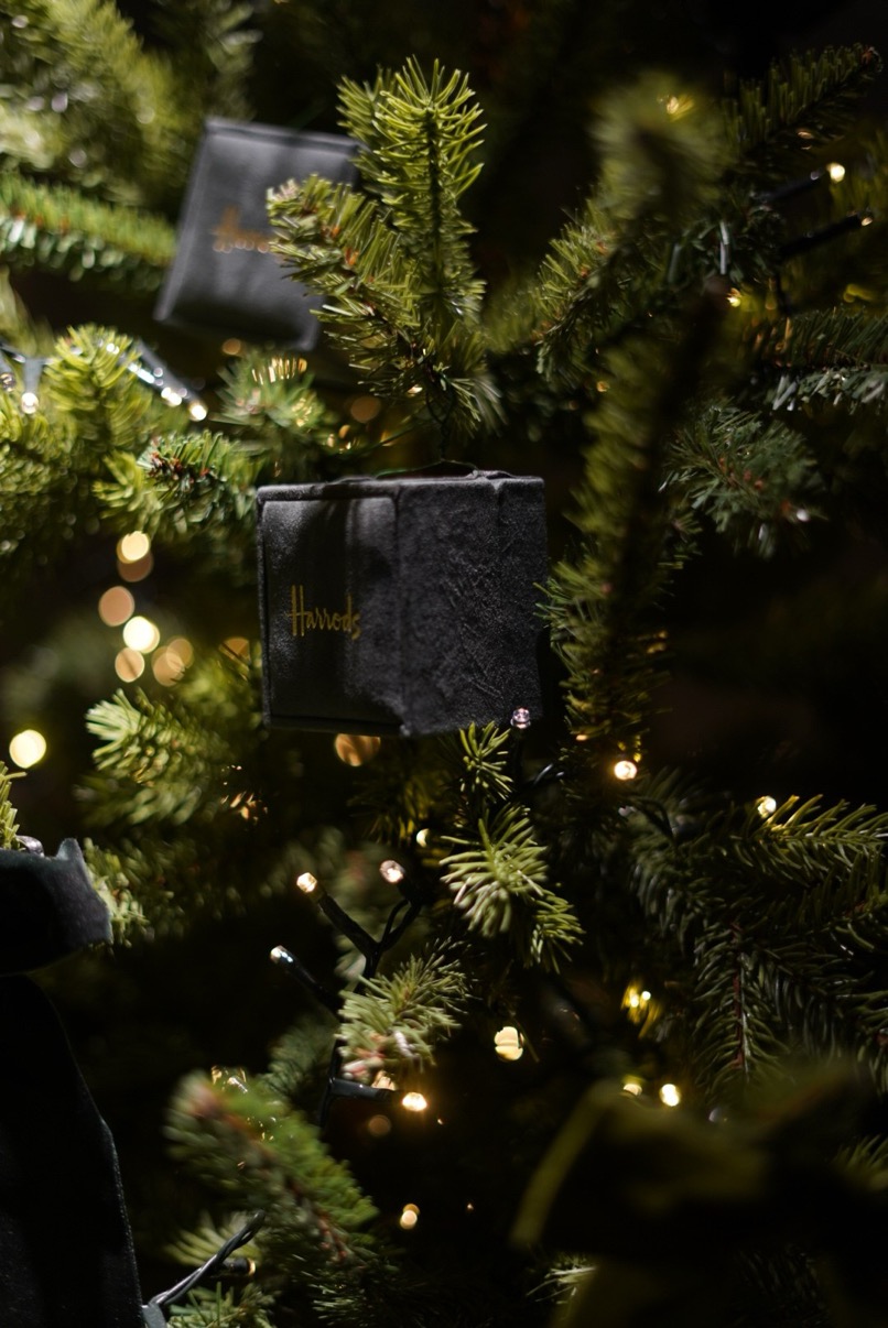 Harrods branded black gift boxes as ornaments in a lit Christmas tree, London