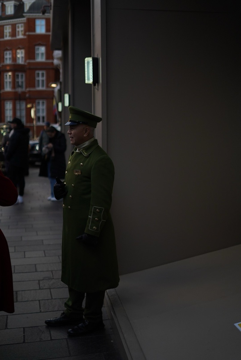 Doorman in green uniform at the entrance threshold, Harrods, London