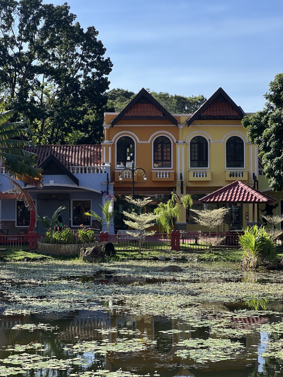 Yellow colonial building with red roof set within tropical trees, Langkawi