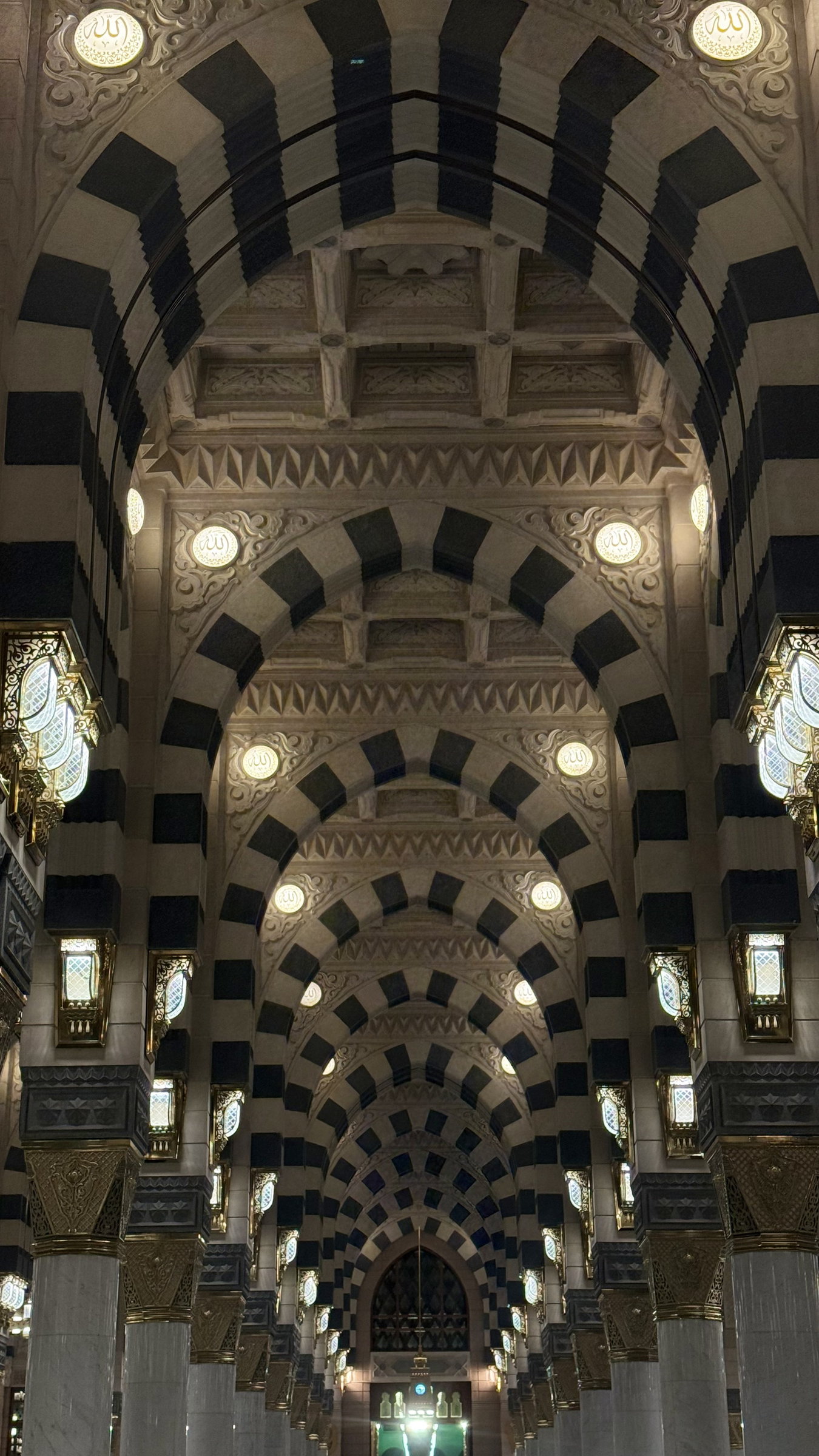 Interior corridor with alternating stone arches and wall lamps, Al-Masjid an-Nabawi, Madinah al-Munawwarah