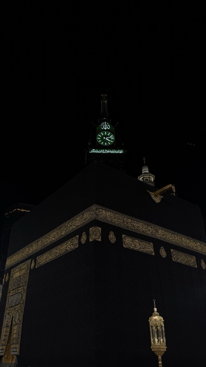 Kaaba corner at night with gold calligraphy and clock tower above, Makkah al-Mukarramah