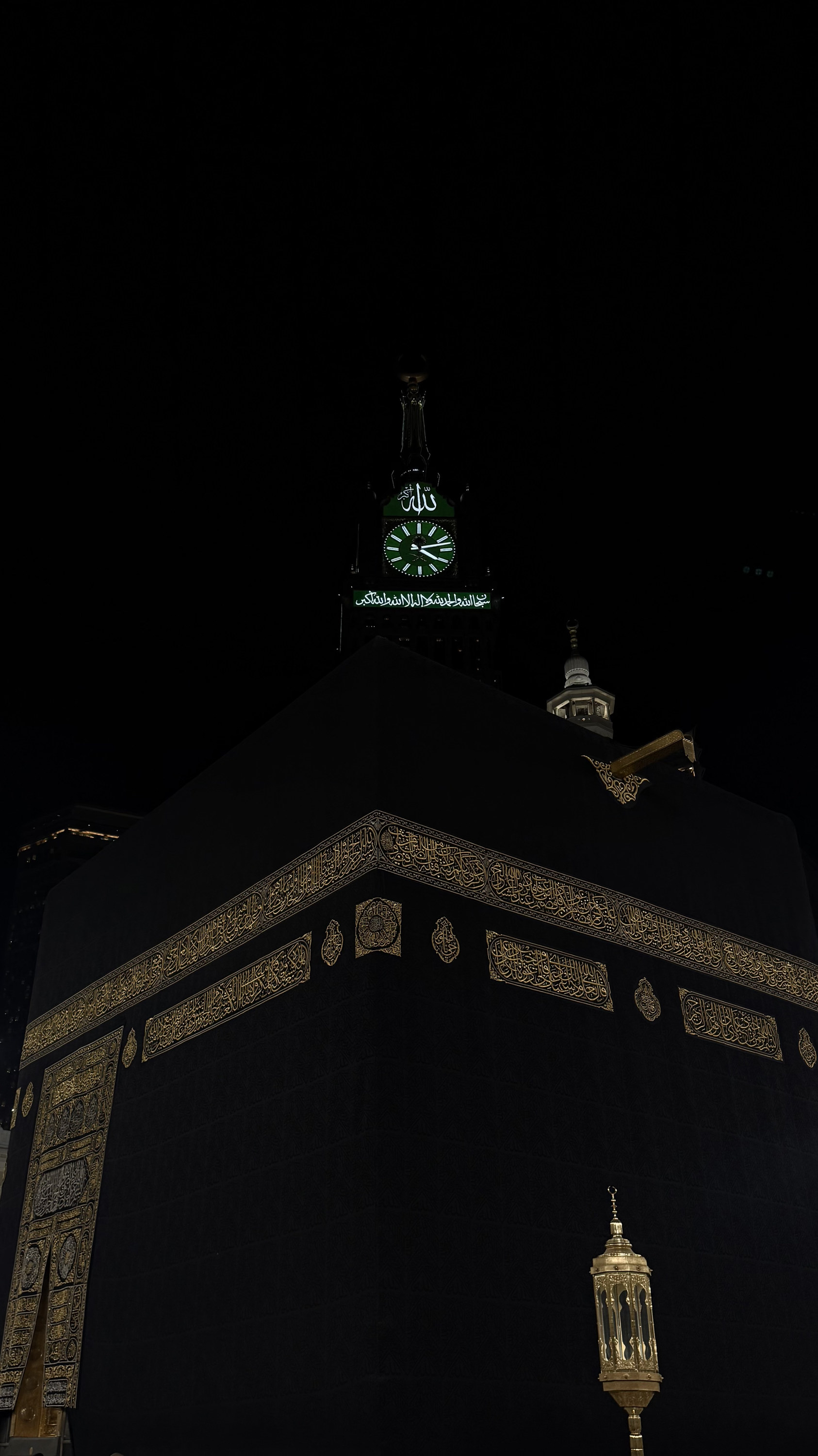 Kaaba corner at night with gold calligraphy and clock tower above, Makkah al-Mukarramah