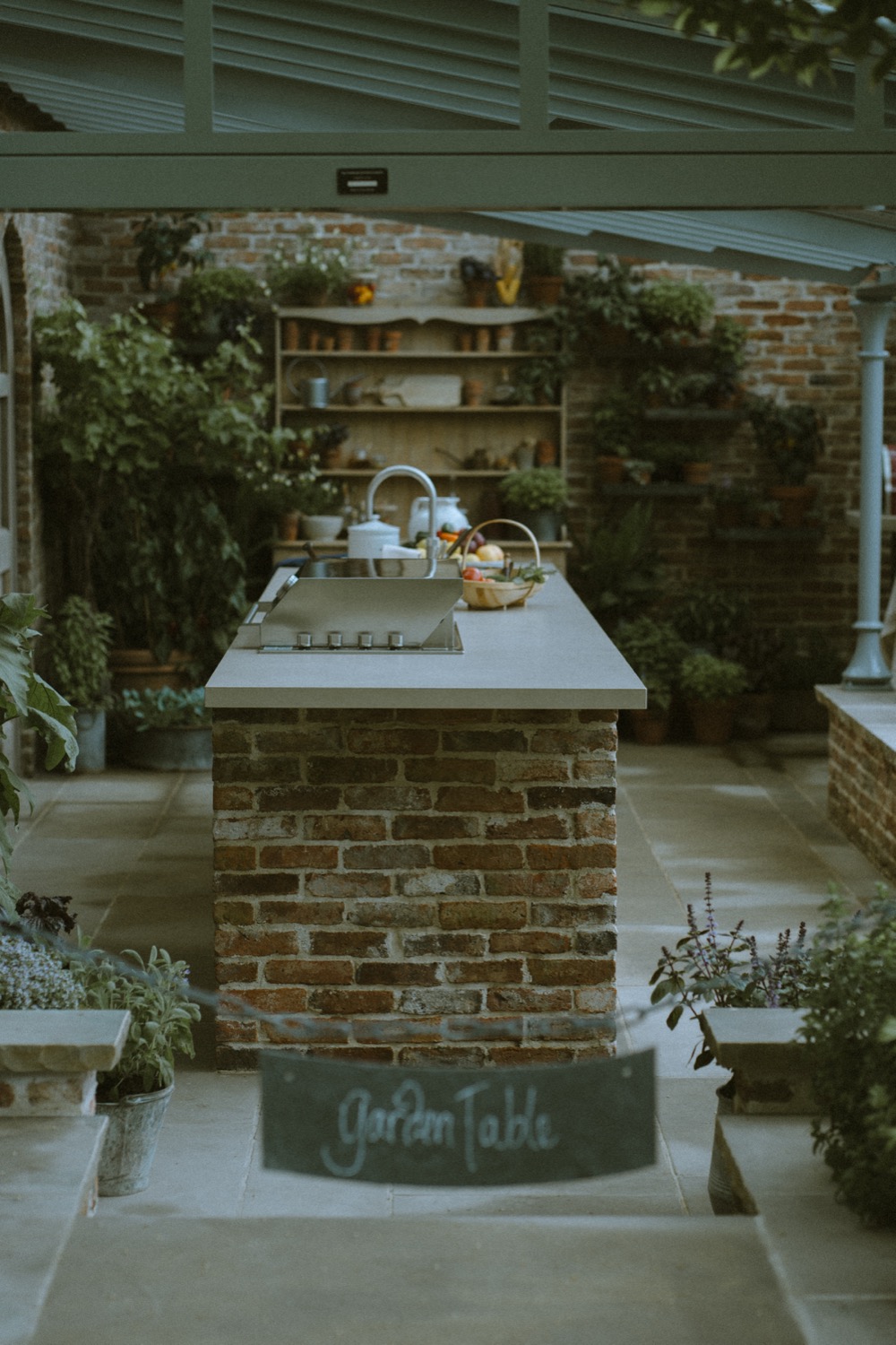 The brick kitchen island with its chalk Garden Table sign, The Savills Garden, RHS Chelsea Flower Show, London