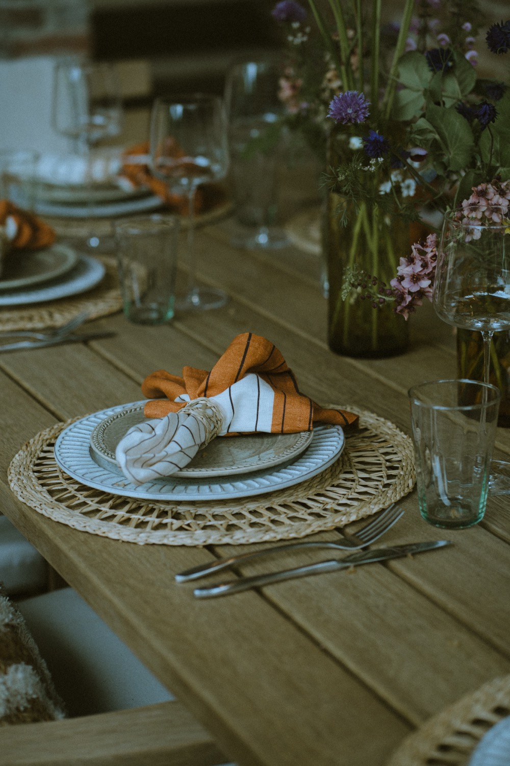 A place setting with a knotted napkin, rattan charger and meadow flowers, The Savills Garden, RHS Chelsea Flower Show, London