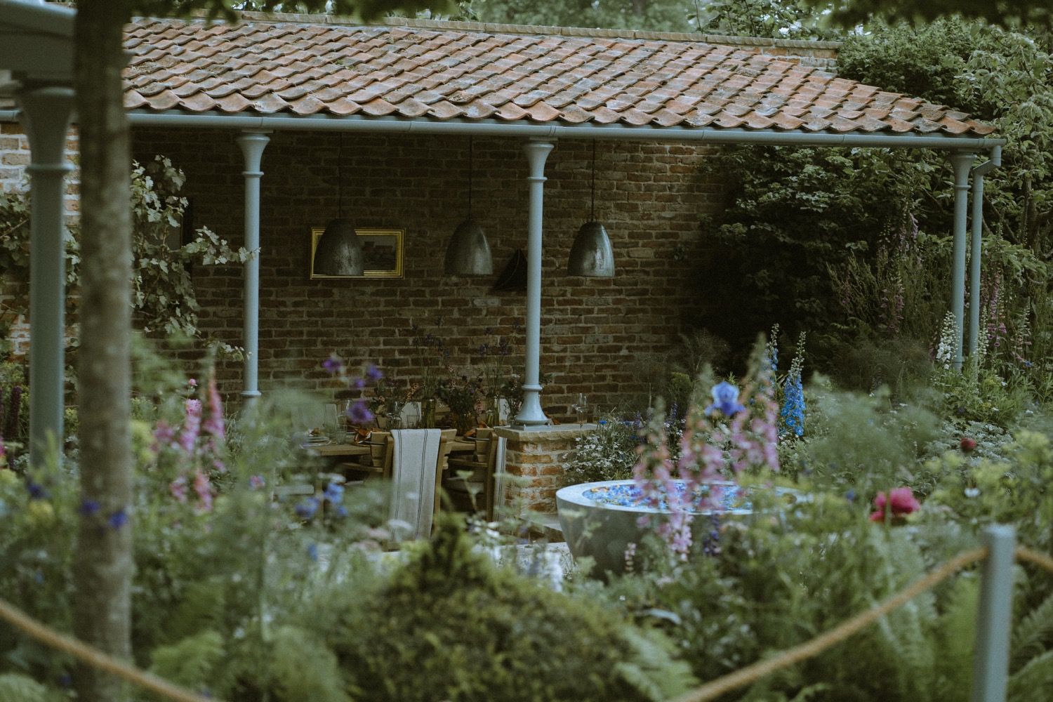 The pavilion seen from outside through foxgloves and delphiniums, The Savills Garden, RHS Chelsea Flower Show, London