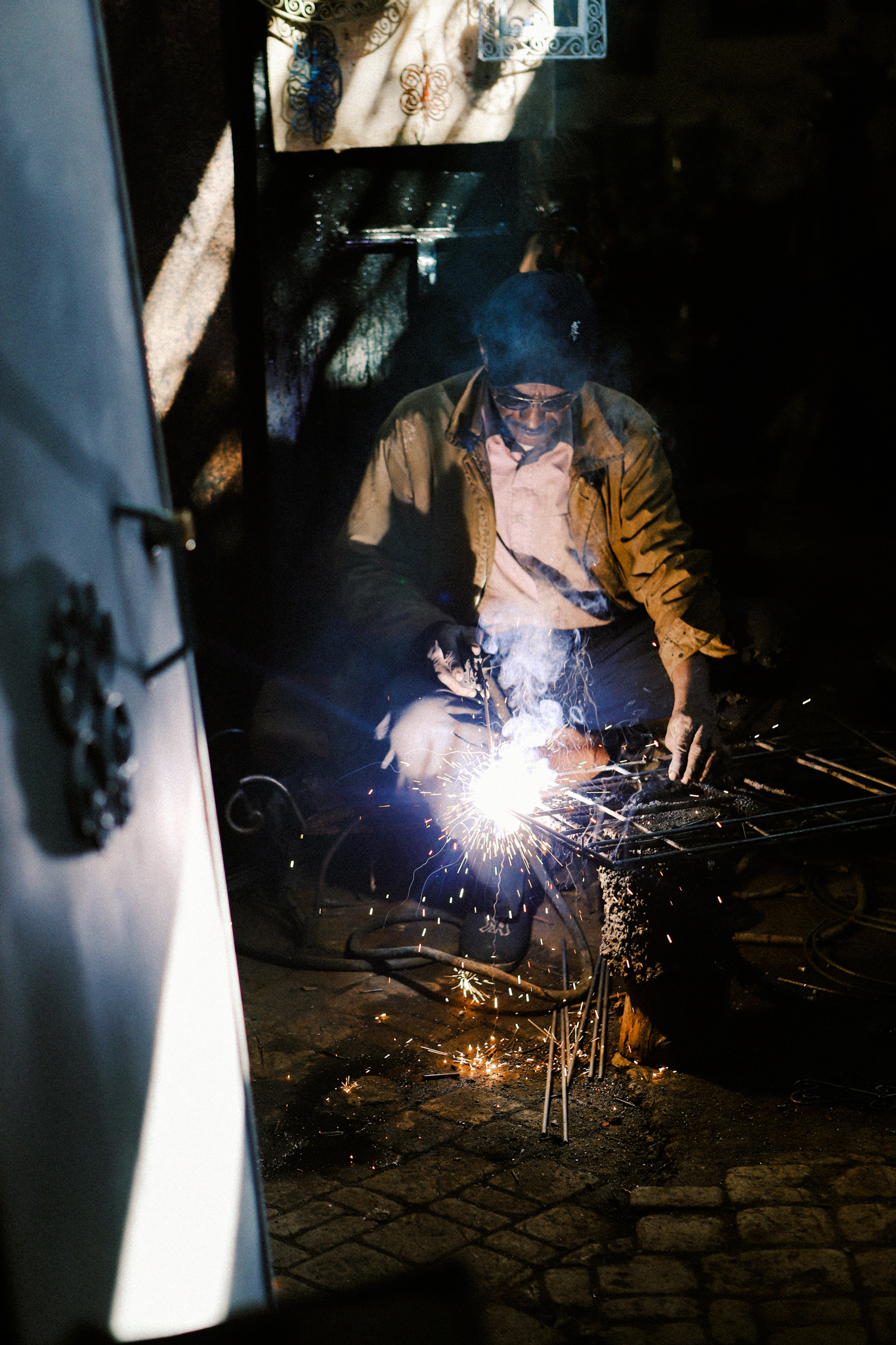 A welder at work in a dark doorway, Marrakech