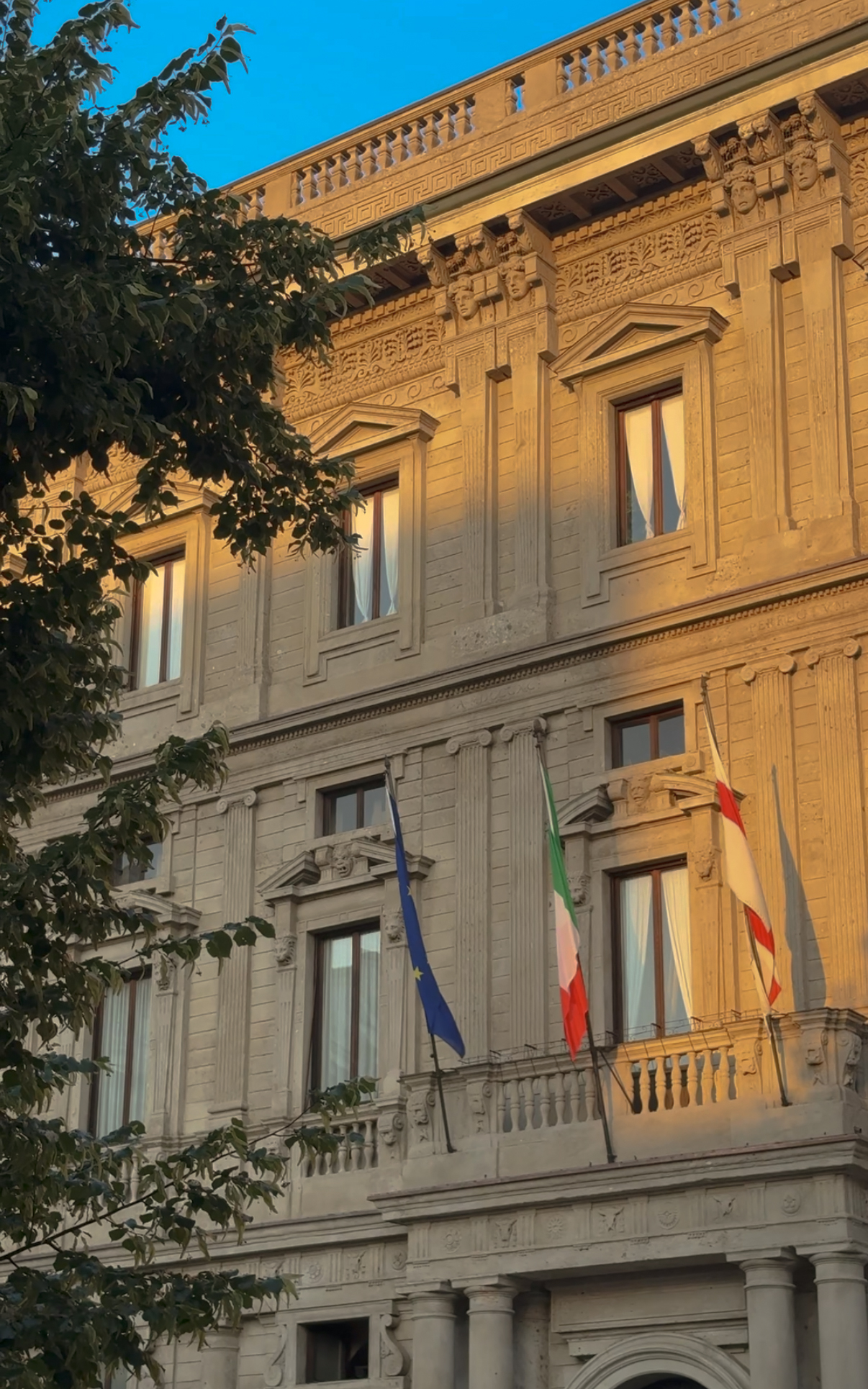 Civic facade with flags in evening light, Milan