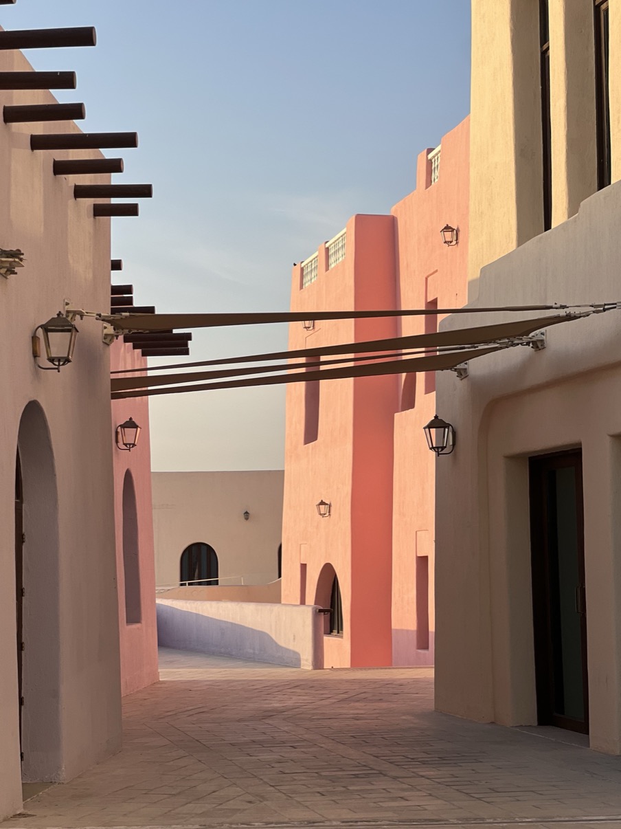 Coral street passage with canopy and evening light, Mina District, Doha