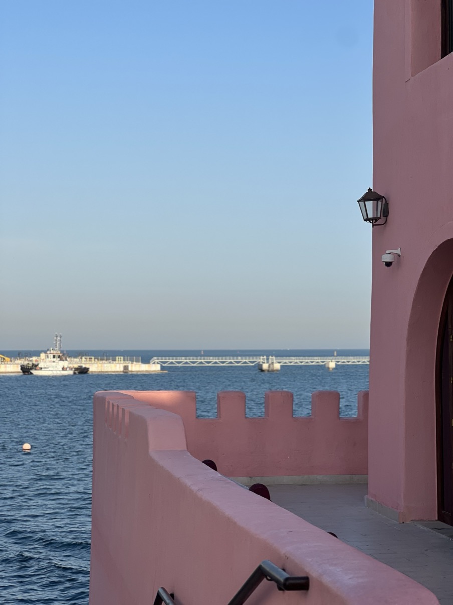 Pink harbour wall with lantern and sea beyond, Mina District, Doha