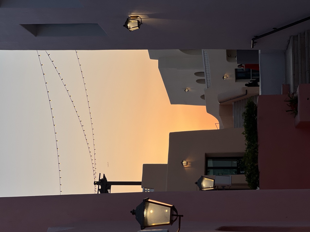 Warm sunset rooflines with lit street lamps and string lights, Mina District, Doha