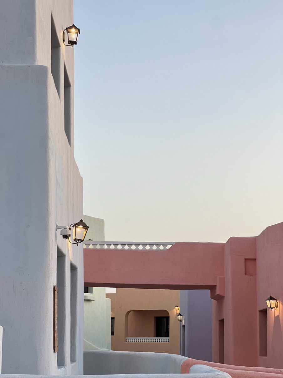 Pastel façades in lavender, white, pink and sand at dusk with lit lanterns, Mina District, Doha