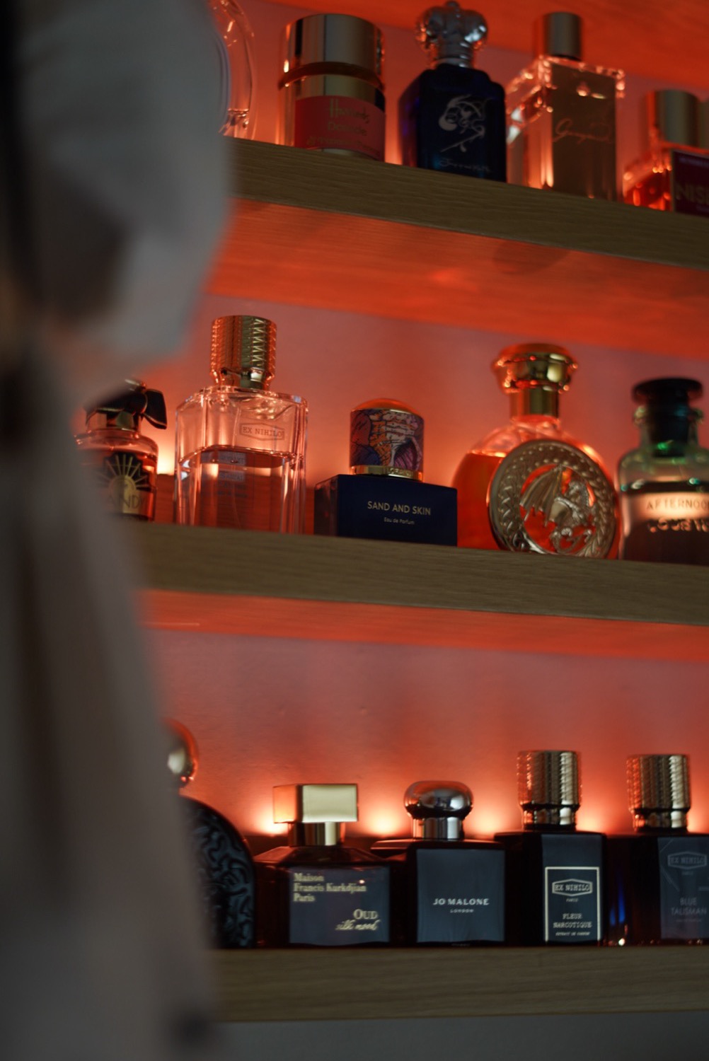 Fragrance collection on a lit shelf, home