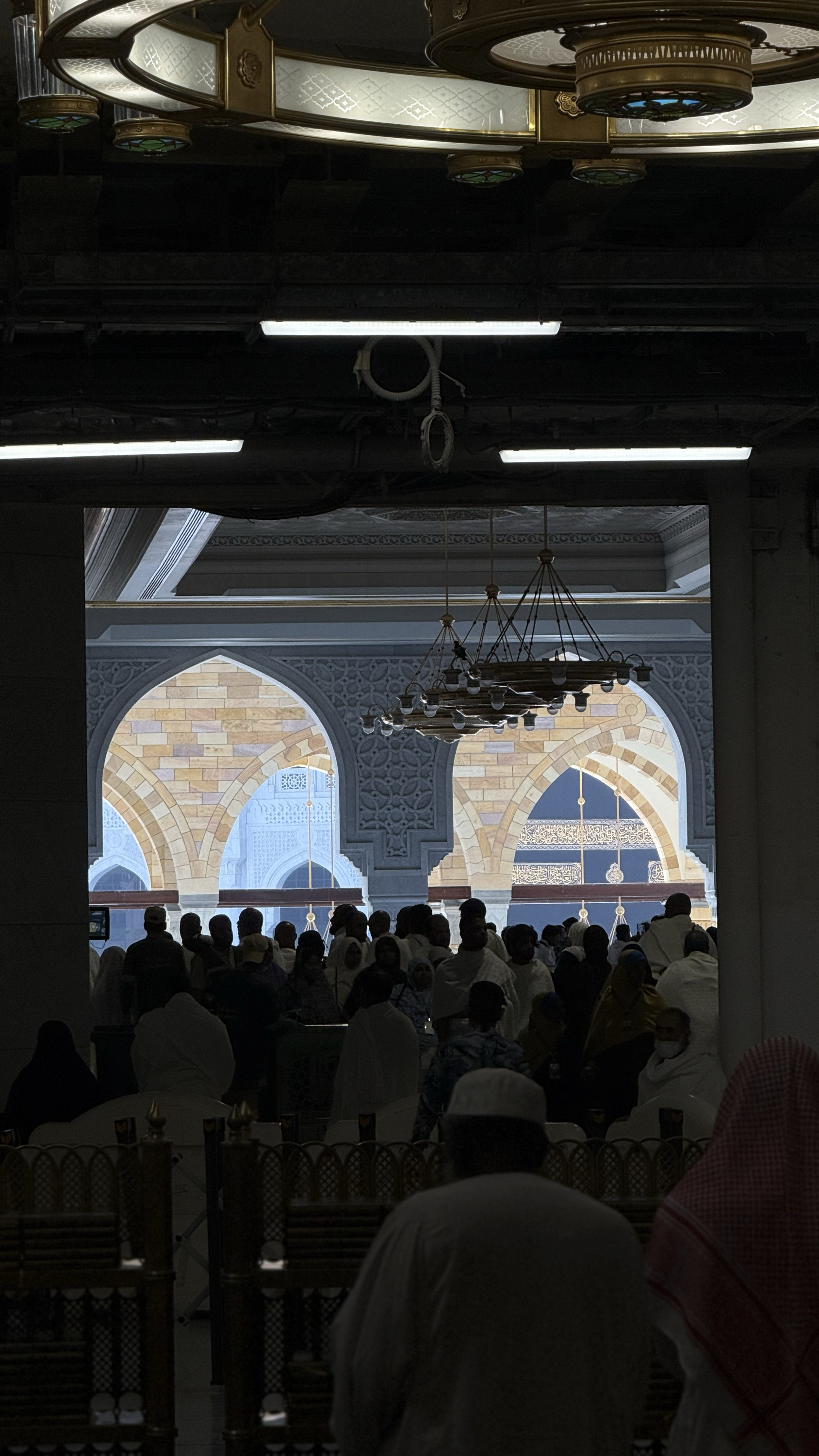 Worshippers cut out in black against the lit arches of the mosque, Nearness