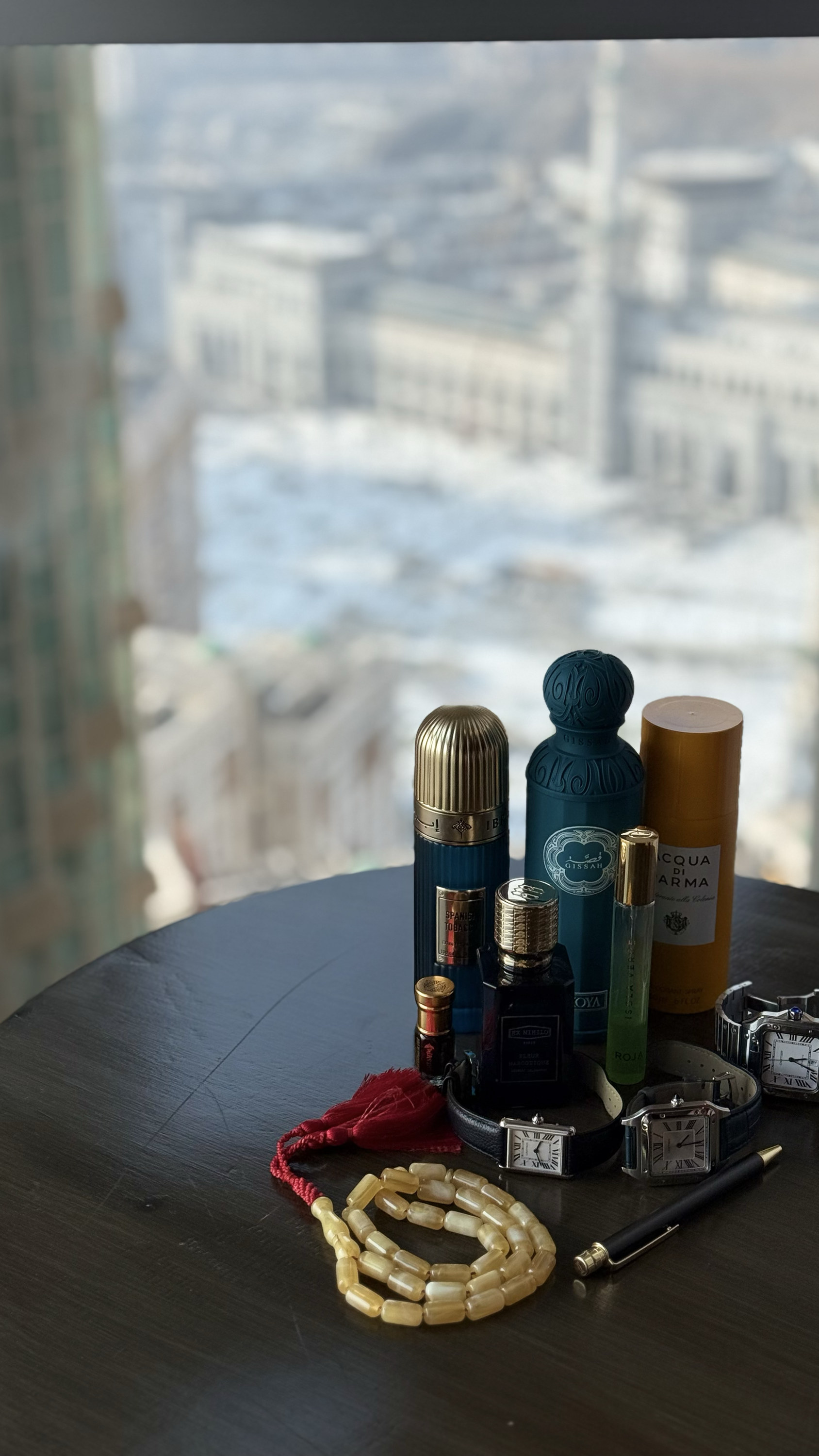 Attar bottles and prayer beads on a table, the sanctuary beyond the window, Makkah