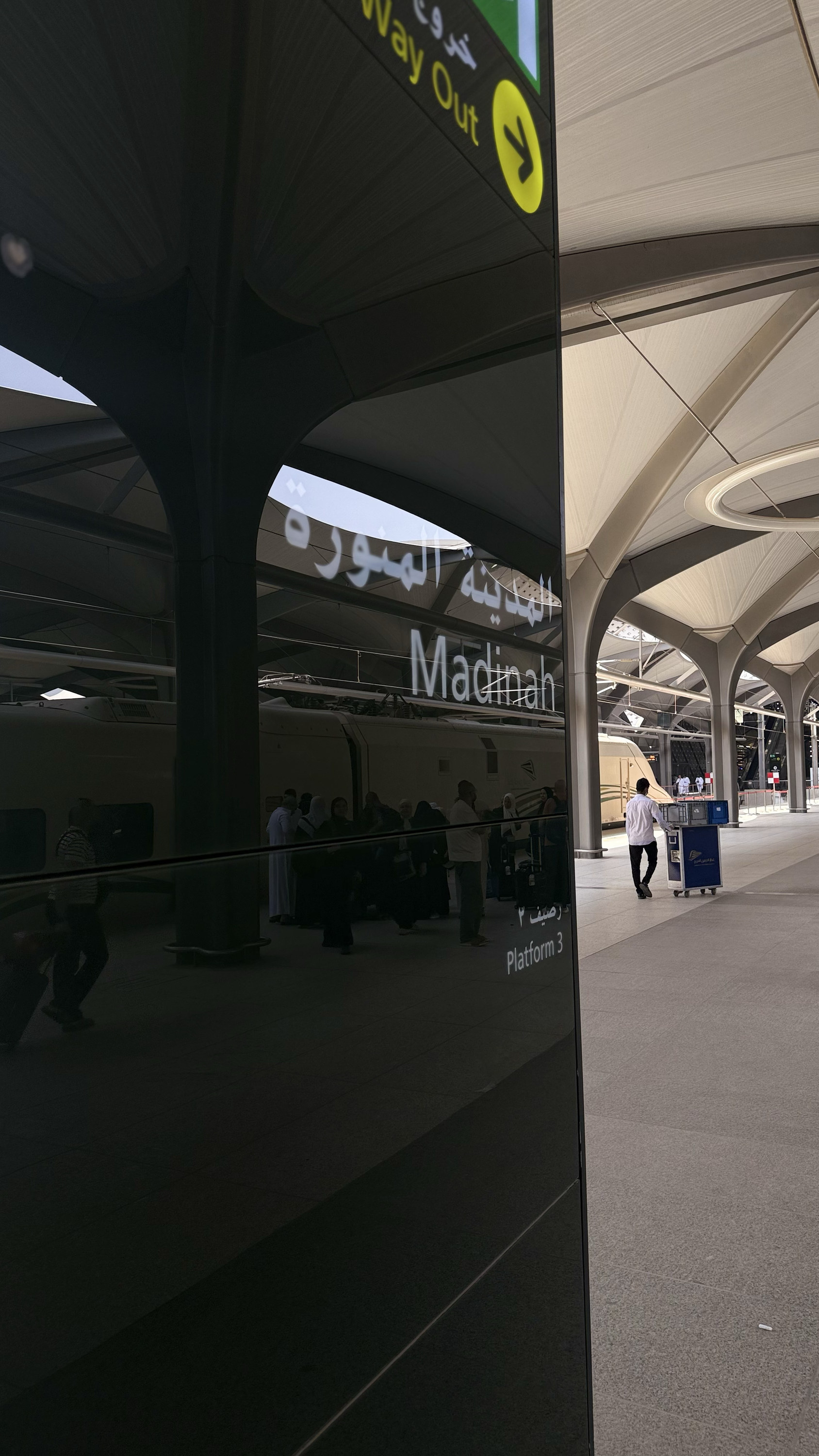 A lone porter pushing a cart away down an empty platform, Madinah, Nearness