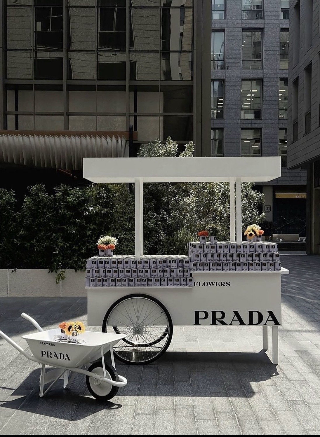 A Prada flower cart standing white against courtyard greenery