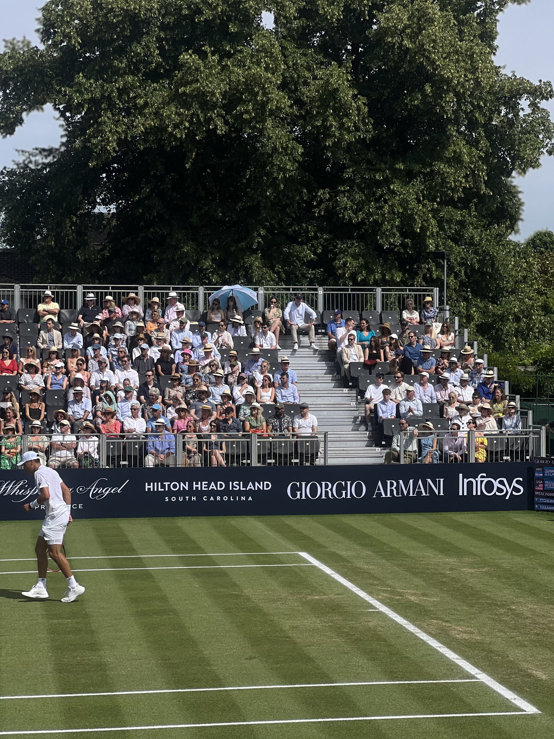 Grass-court tennis before a full terrace, Giorgio Armani boards along the line
