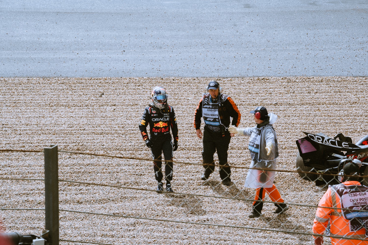 Red Bull F1 car stationary in the gravel trap after an incident, marshals attending