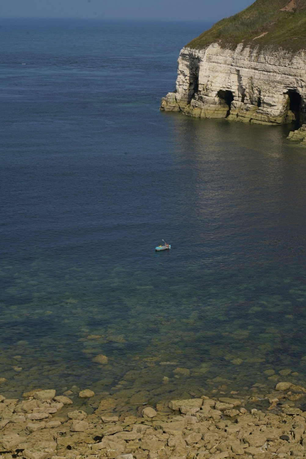 Sea cave and small boat on clear water