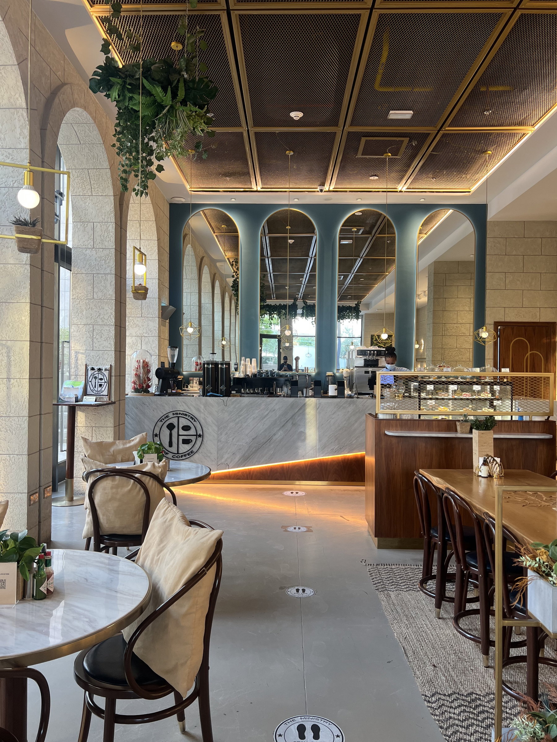 Arched cafe interior in soft green and timber, counter under pendant light