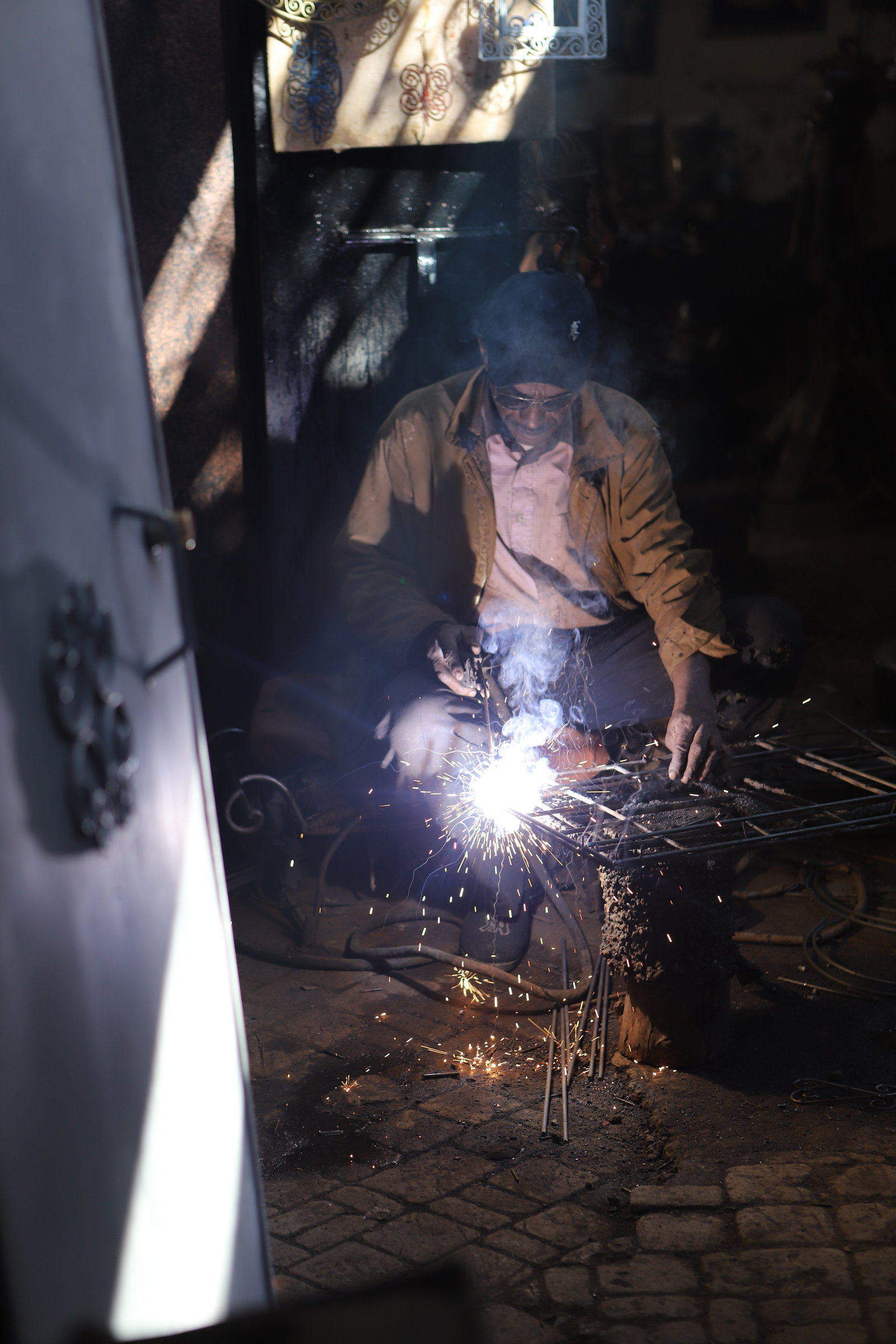 A blacksmith welding in a dark workshop, sparks against the shadow