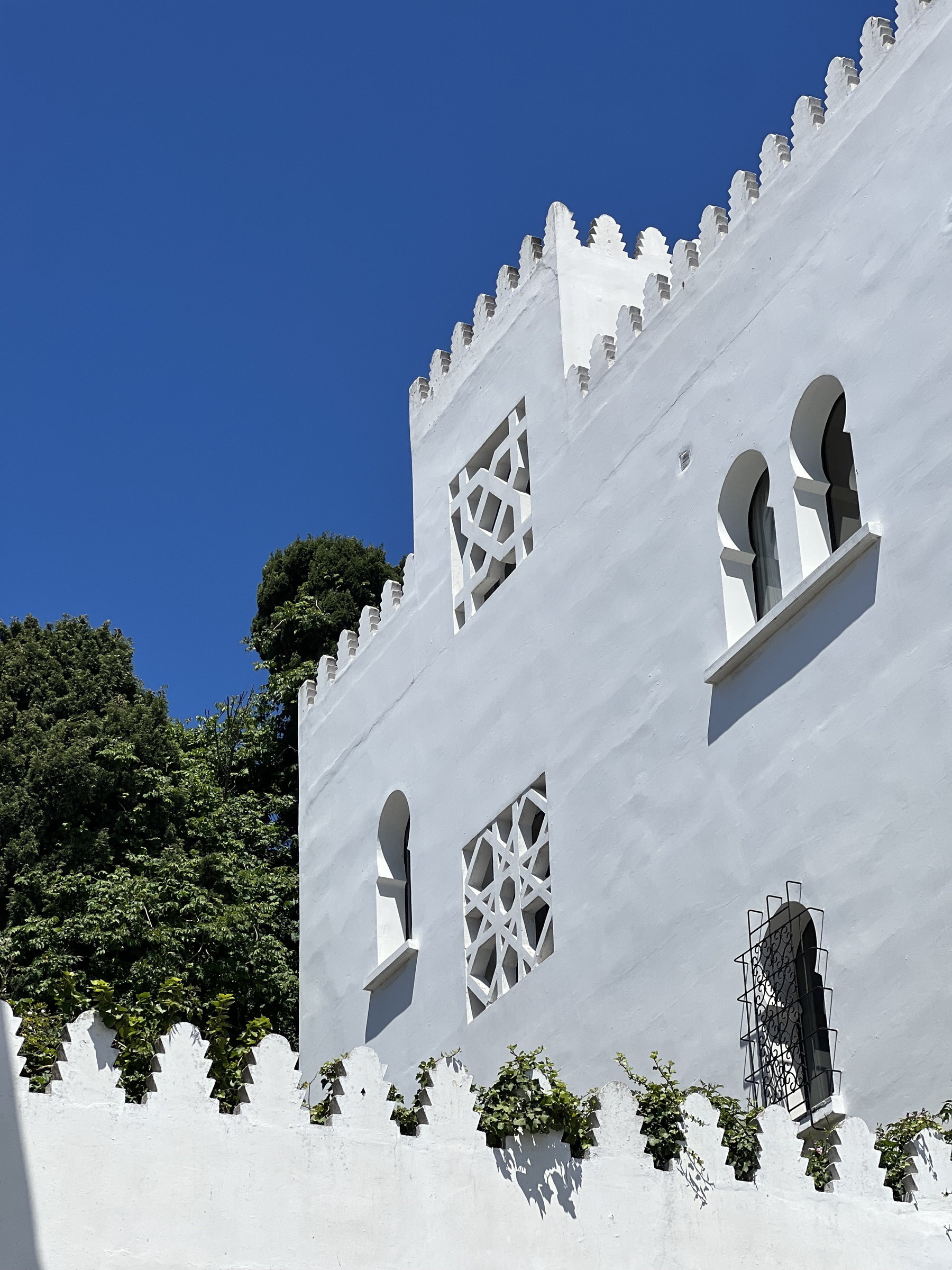 White crenellated facade with pierced screens against a deep blue sky, Tangier